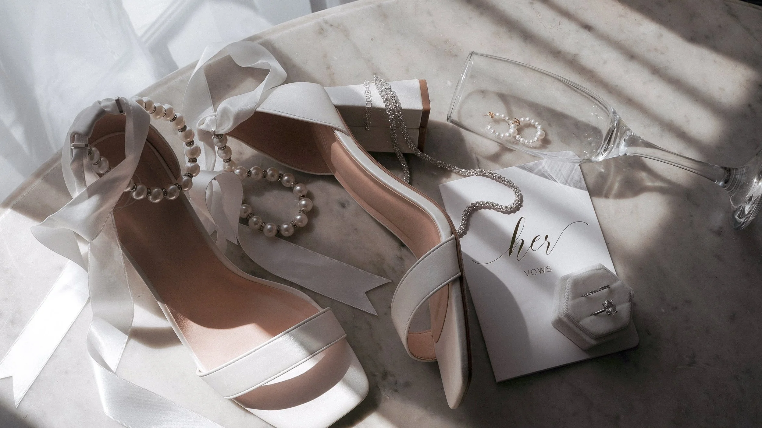 Bridal shoes with pearl straps, pearl earrings, engagement ring and vow book before a Curragh wedding in Kildare