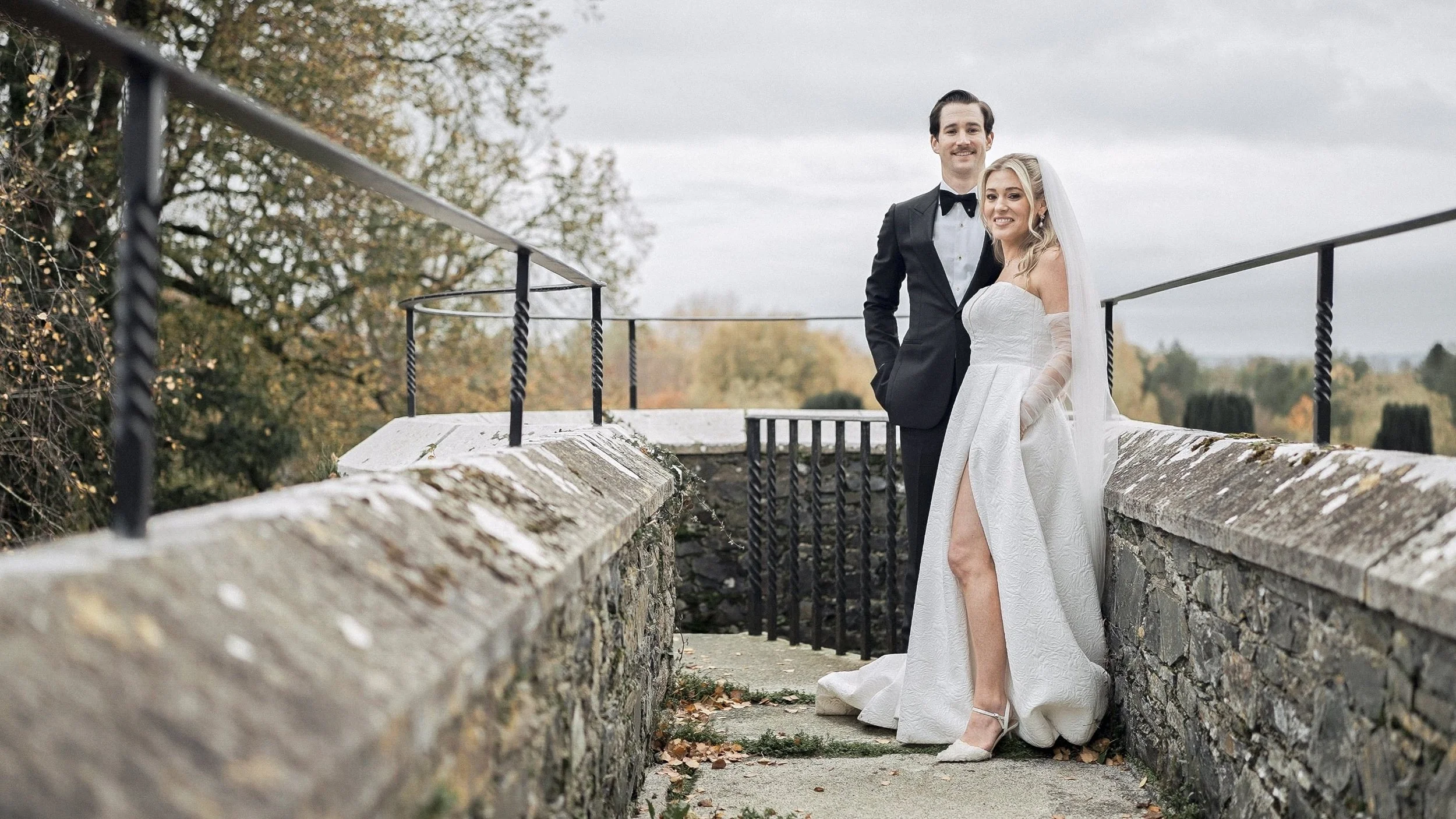 Bride and groom on the old stone walls of Kilkea Castle with autumn trees, Co. Kildare