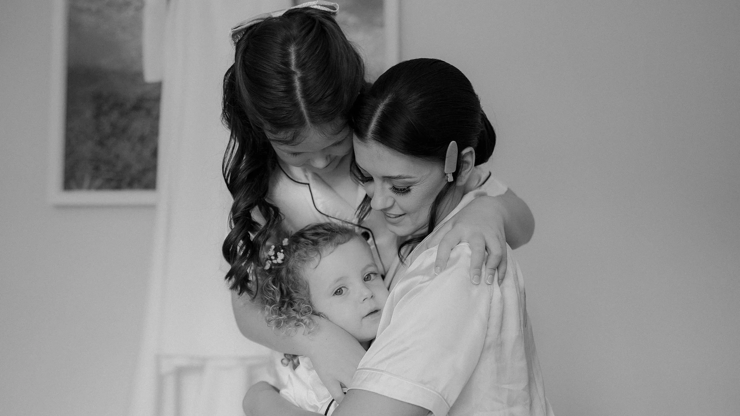 Black and white photo of the bride hugging a little girl while getting ready at Farnham Estate