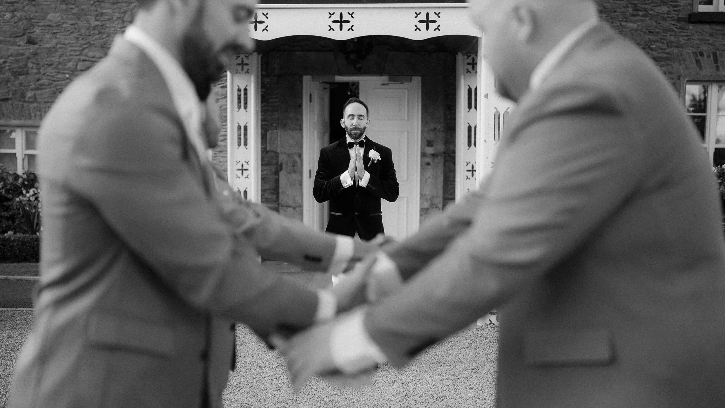 Groomsmen in grey suits greeting each other in front of the Darver Castle porch, with a groom in the doorway