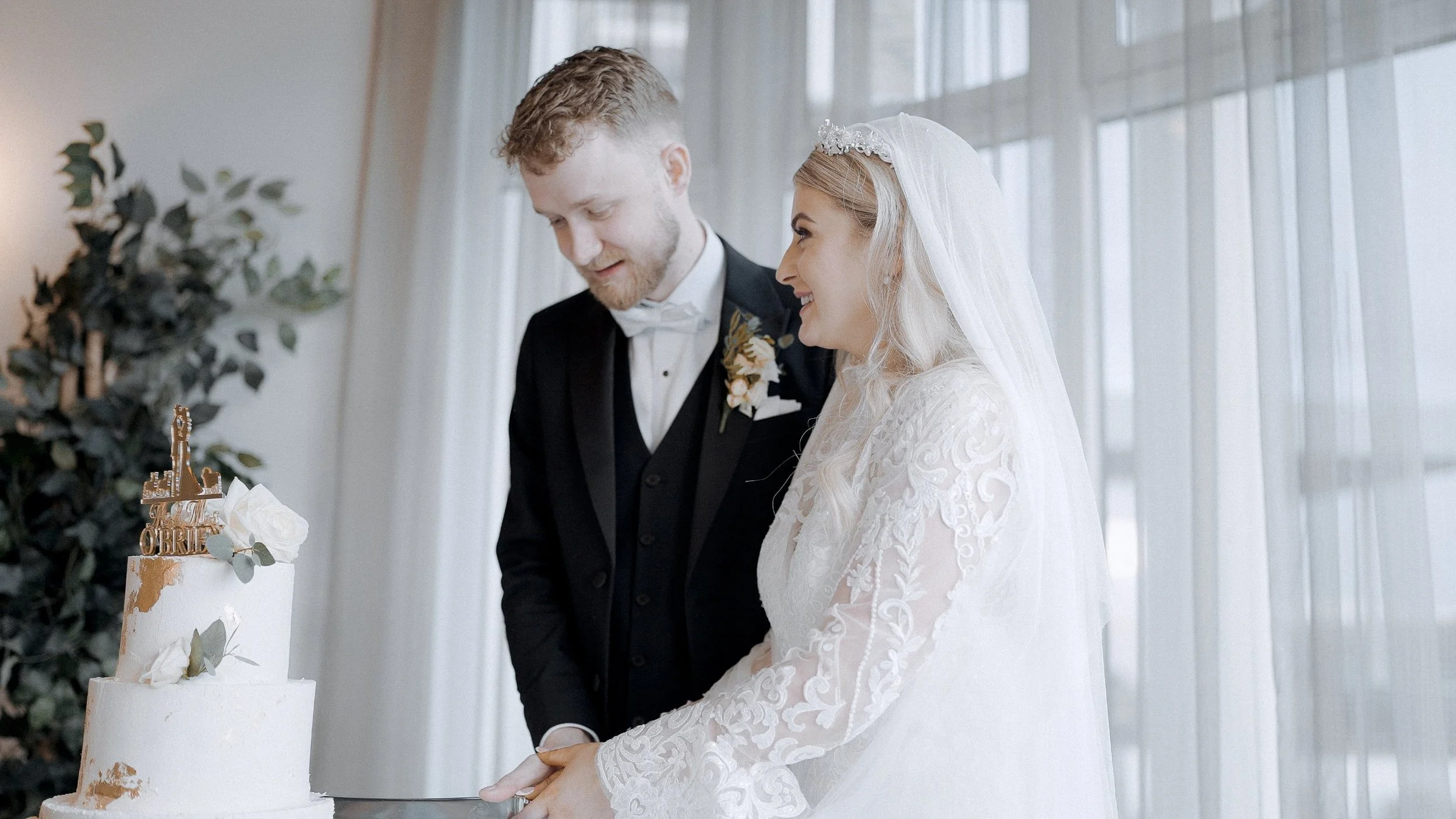 Hannah and Francis cutting their wedding cake by the tall windows at the Armada Hotel, Spanish Point