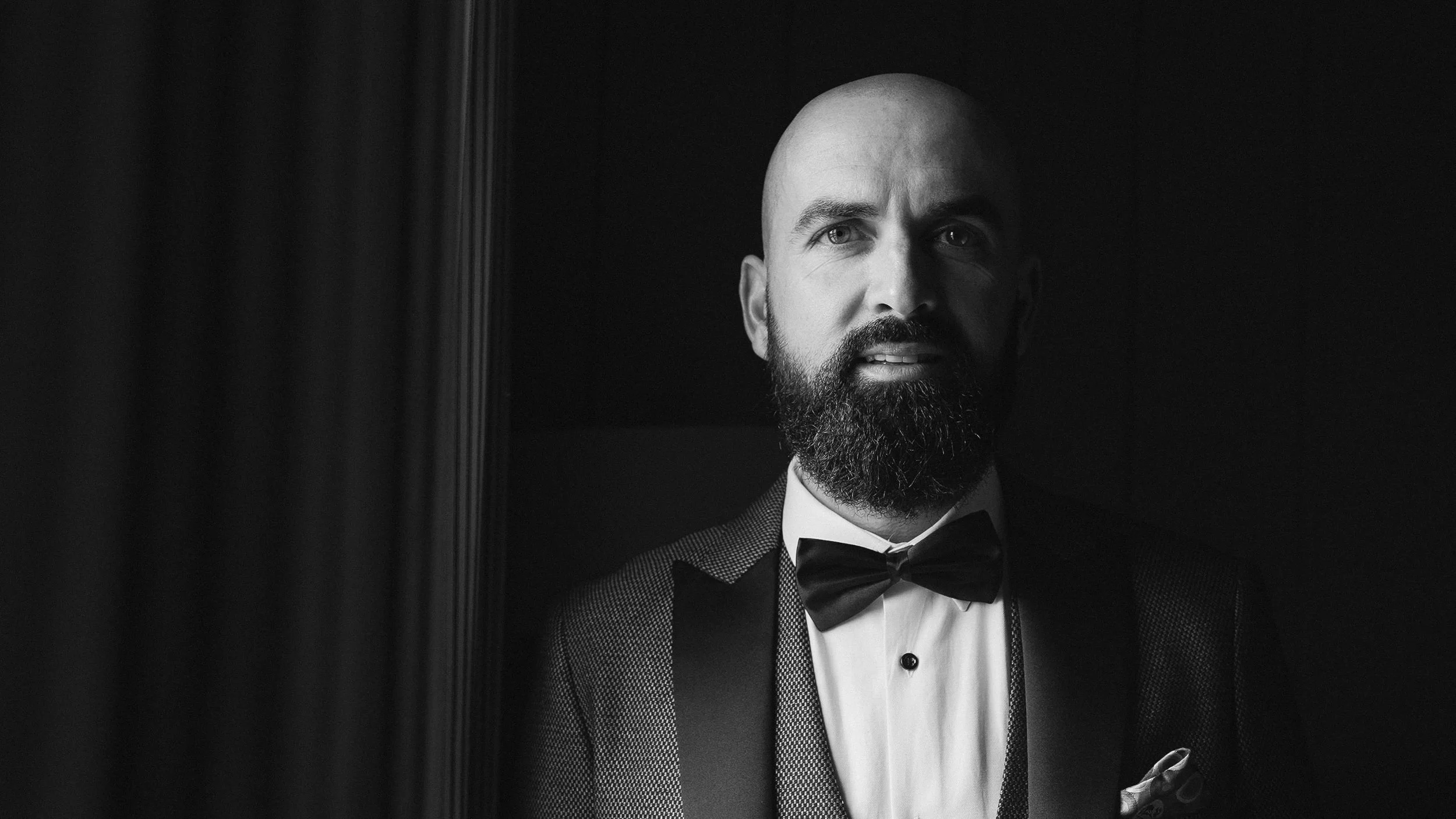 Black and white portrait of the groom in a tuxedo and bow tie before his Glasson Lakehouse wedding