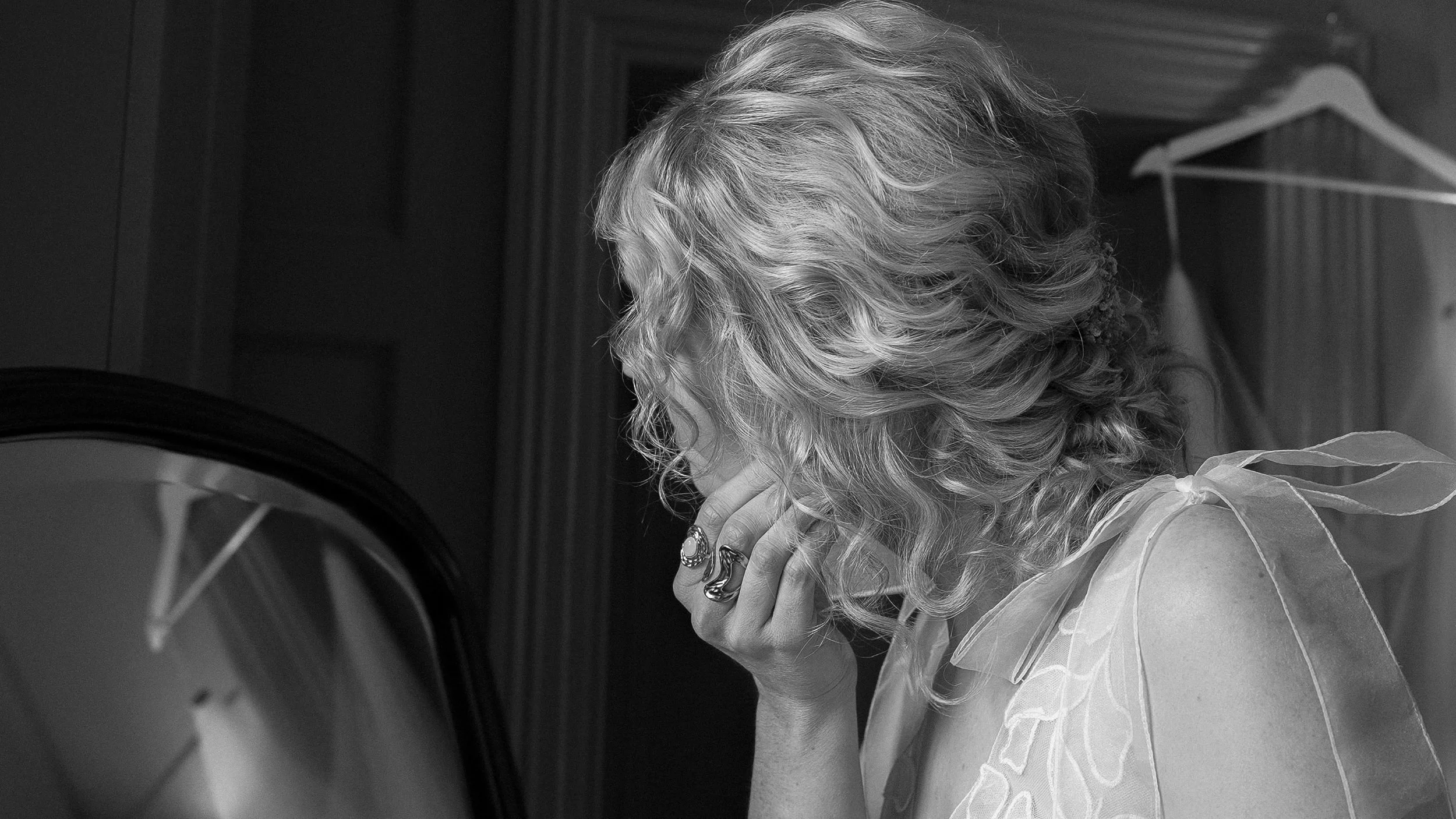 Black and white photo of the bride putting on her earrings in the mirror, Station House Hotel wedding
