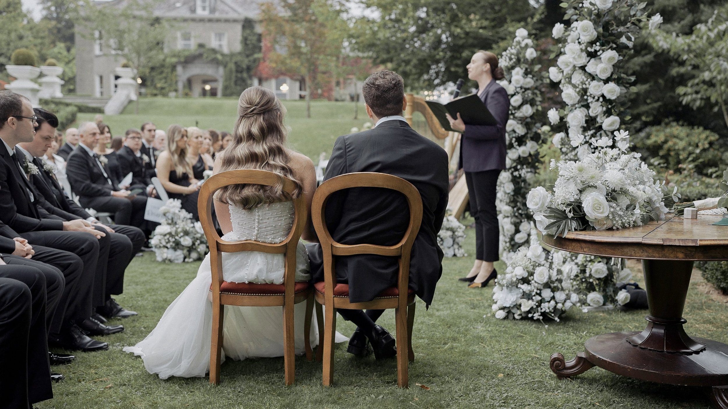 Bride and groom seated before their celebrant with Tinakilly House in the background, Co. Wicklow