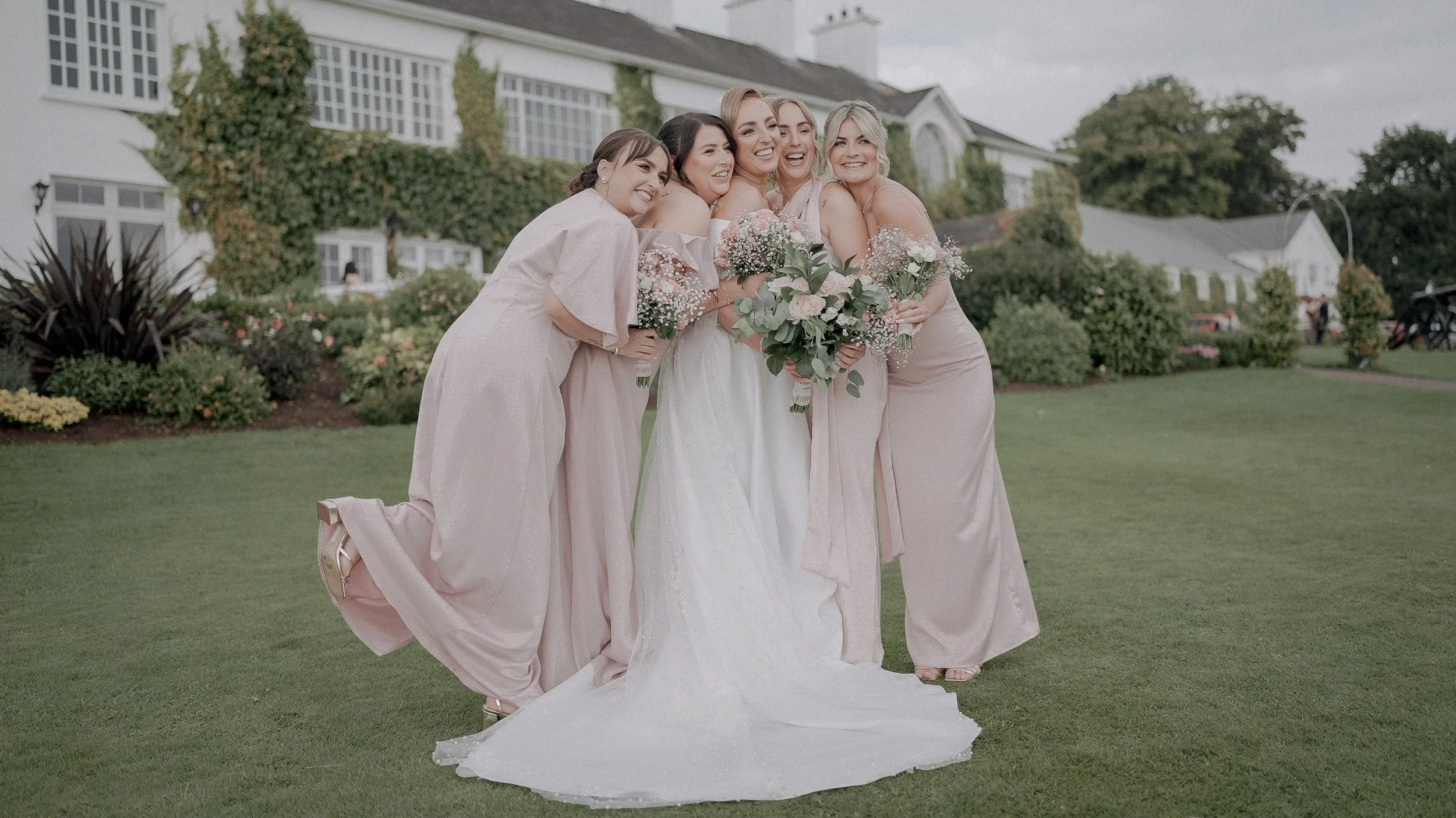Bride with her bridesmaids in blush pink dresses on the lawn in front of Crover House Hotel, Co. Cavan
