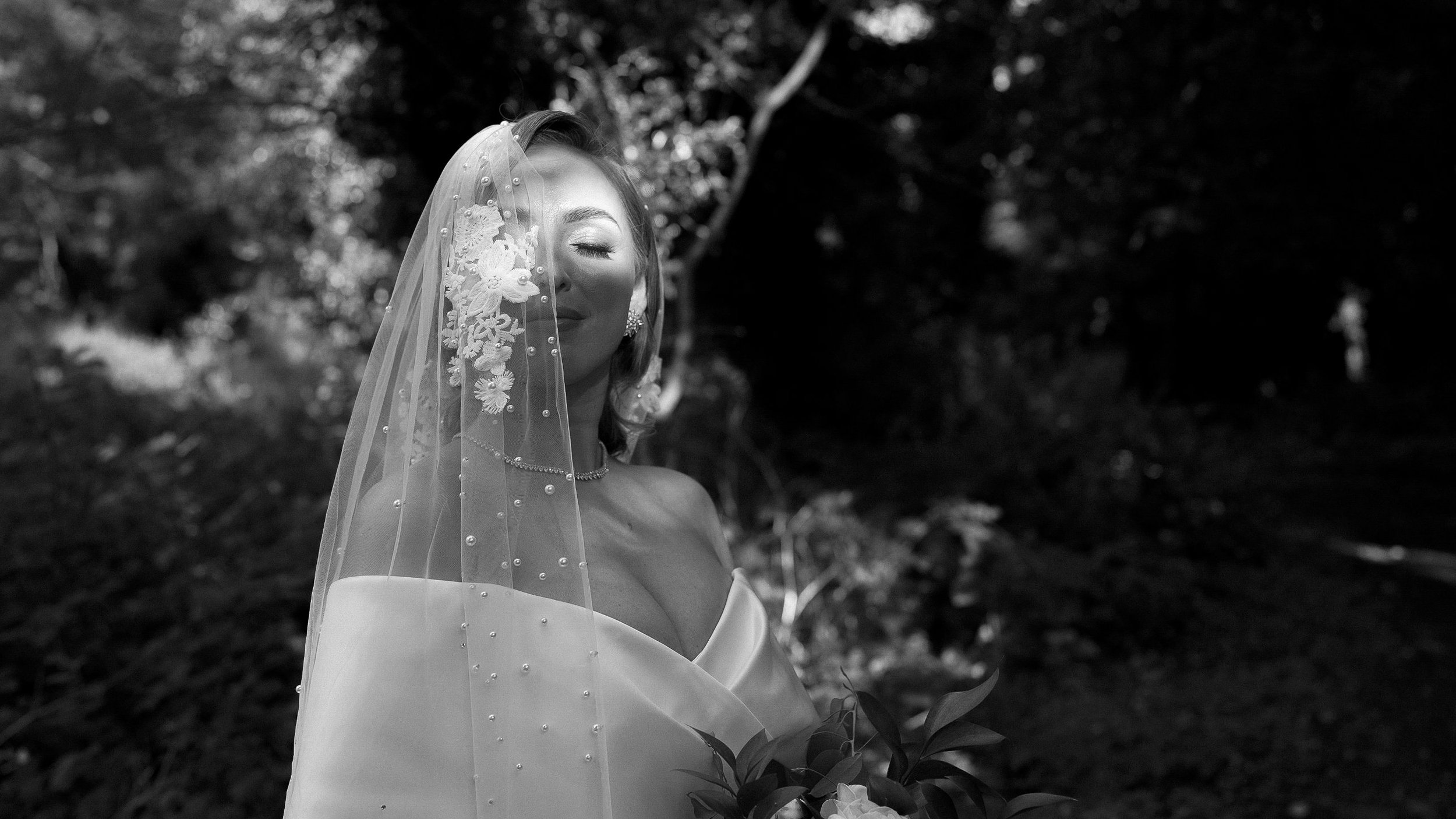 Black and white portrait of the bride under a pearl-studded veil among the trees at Crover House Hotel