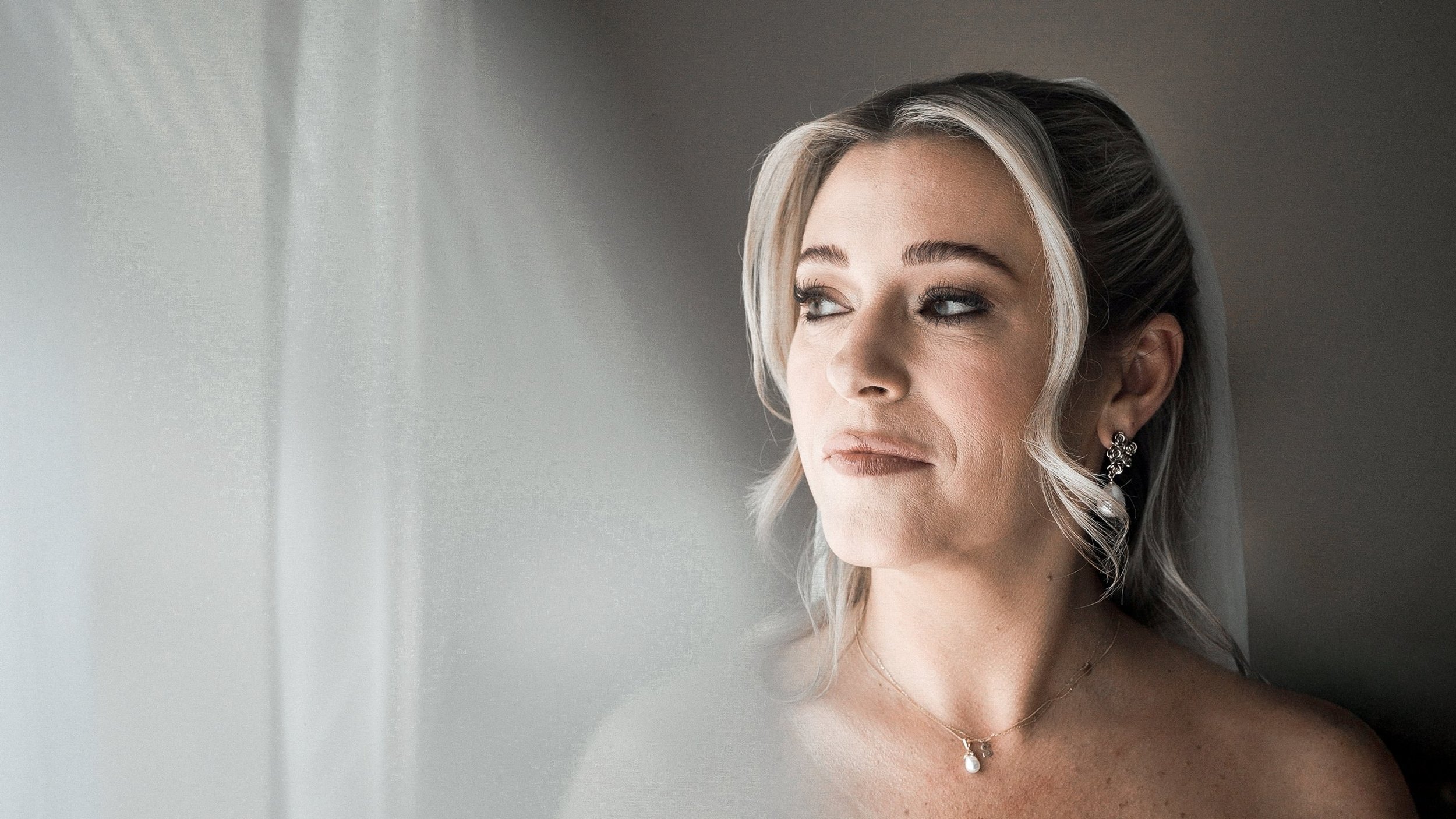 Bride with pearl earrings by the window before her Kilkea Castle wedding, Co. Kildare