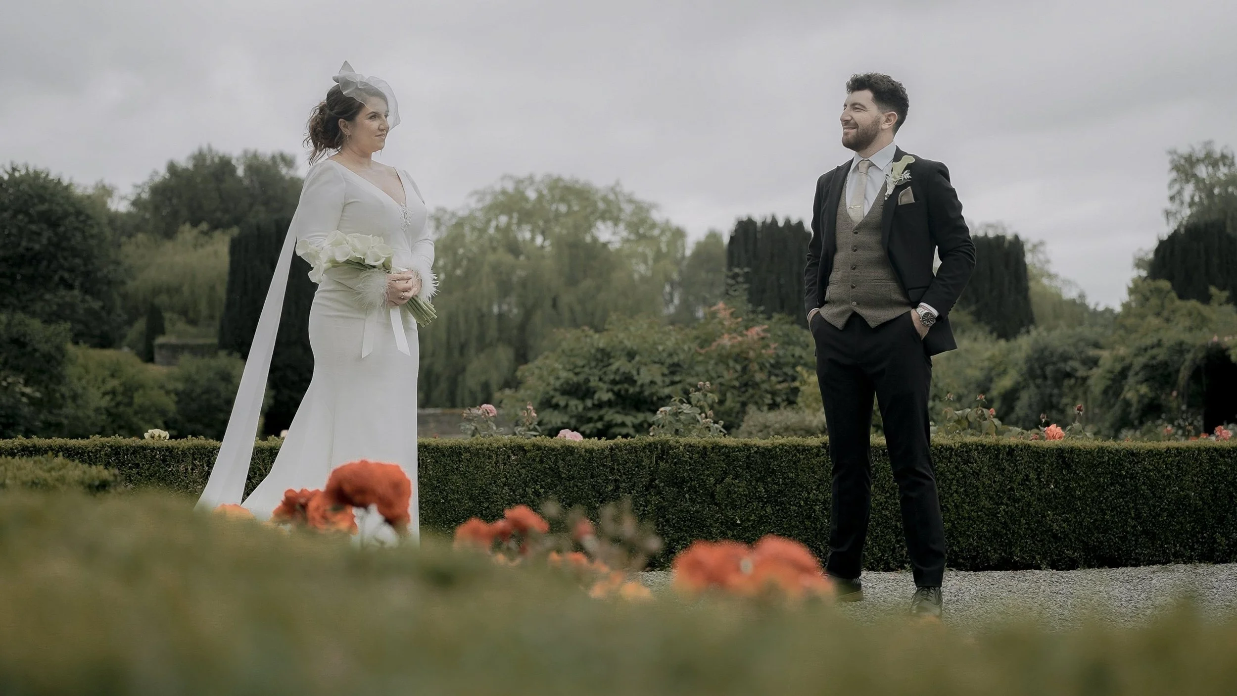 Bride with a calla lily bouquet and groom among the rose beds and box hedges at Kilkea Castle gardens