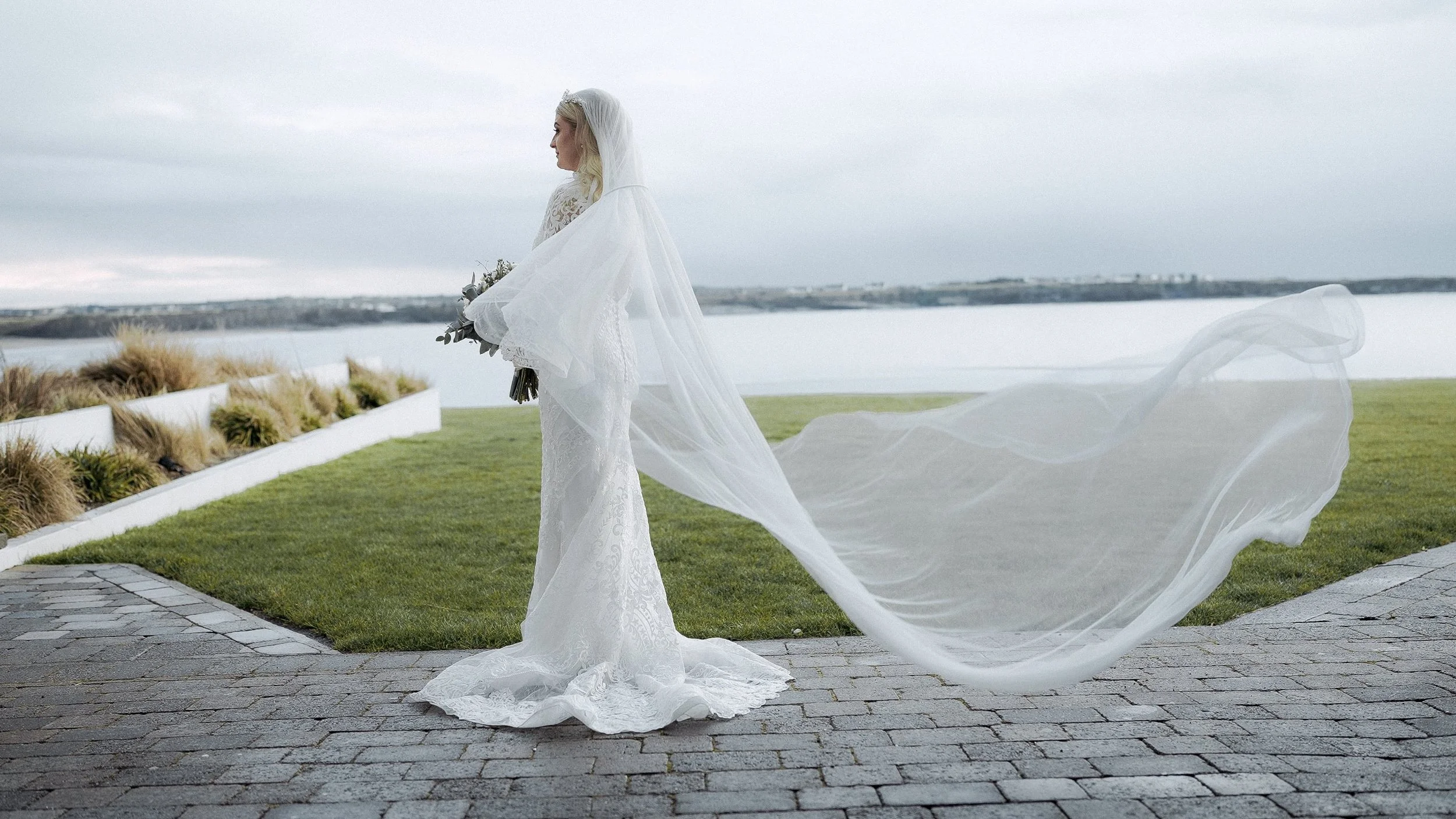 Bride's long veil blowing in the wind above Spanish Point bay at the Armada Hotel, Wild Atlantic Way wedding
