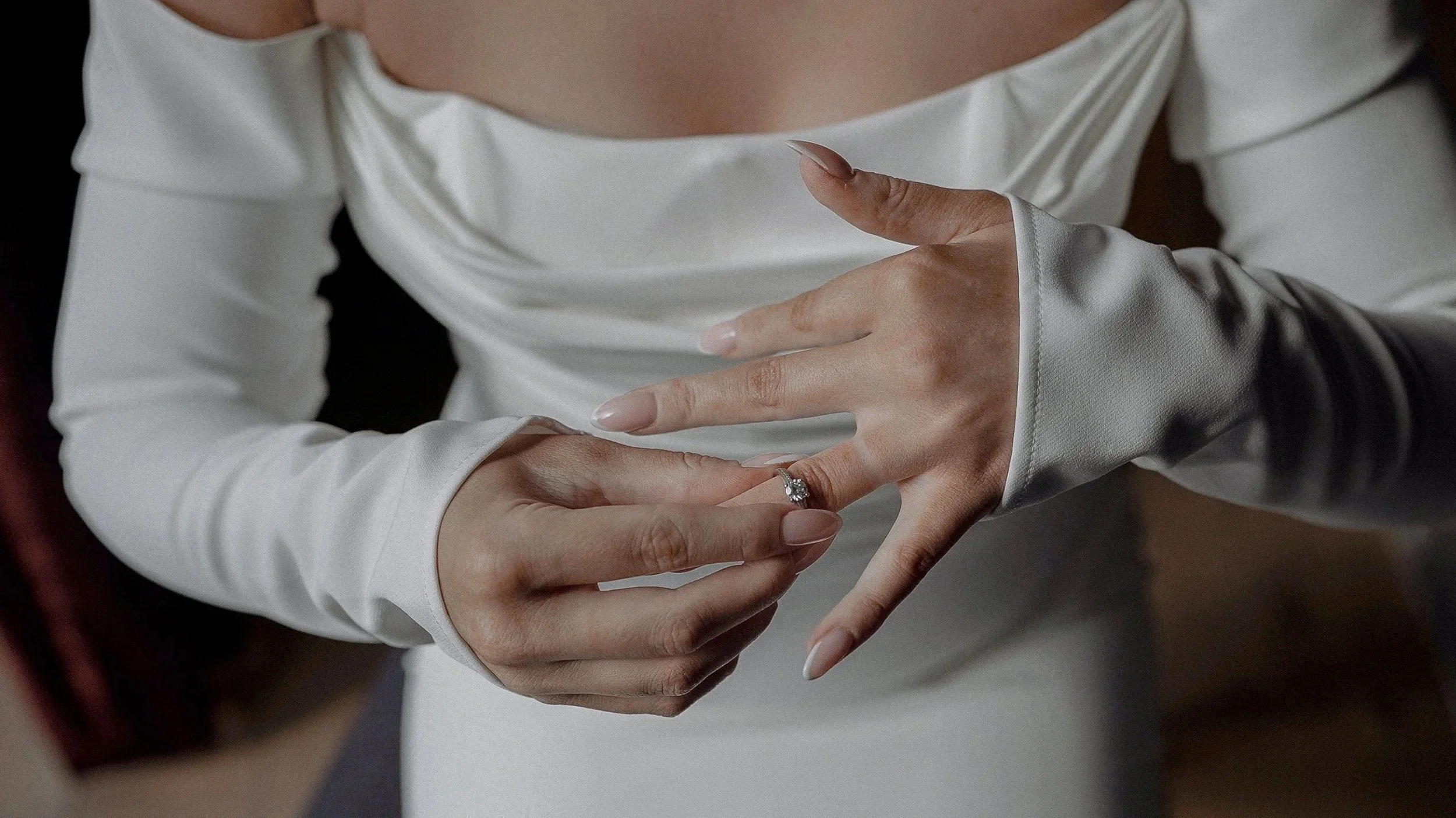 Close-up of the bride adjusting her ring with her off-shoulder wedding dress at Farnham Estate