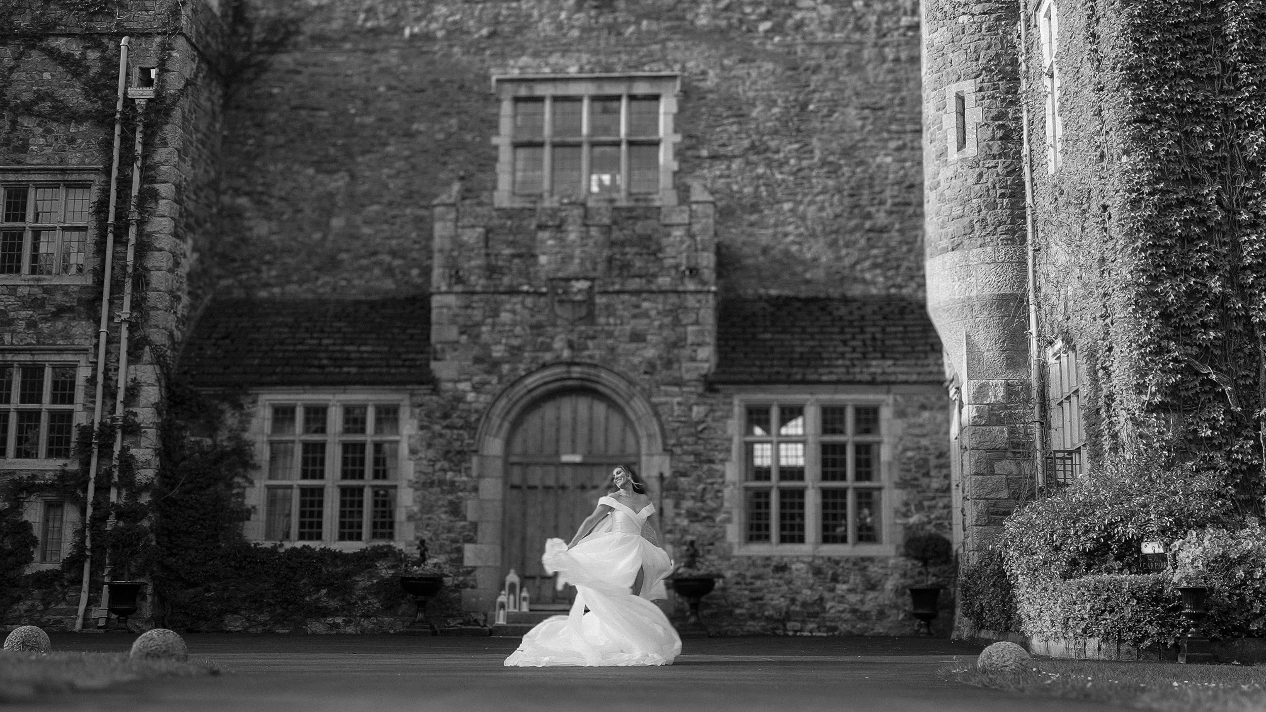 Bride twirling her gown in the courtyard in front of Waterford Castle, black and white