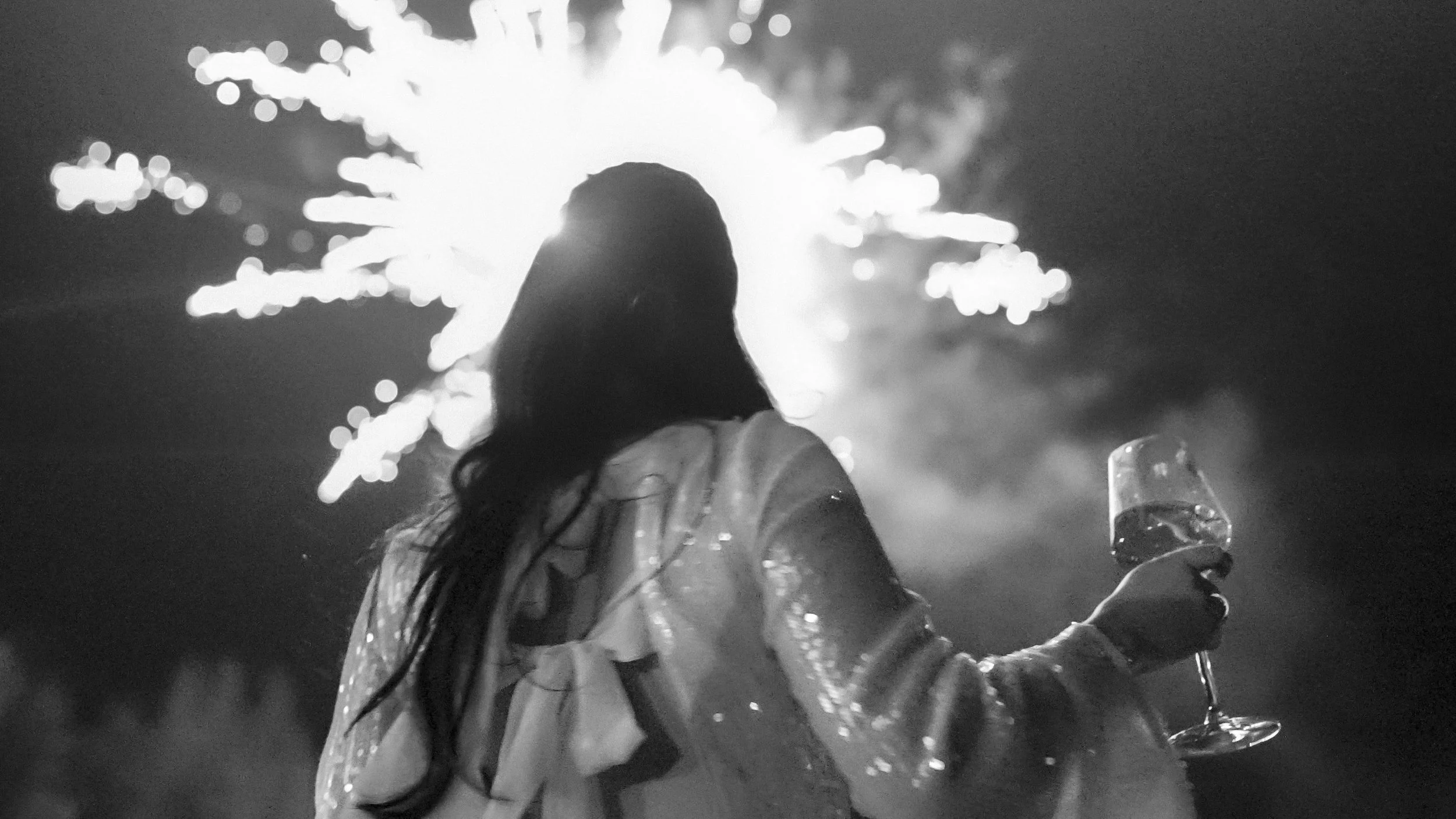 Bride in a sequinned evening outfit watching fireworks over Kilkea Castle with a glass of wine, black and white