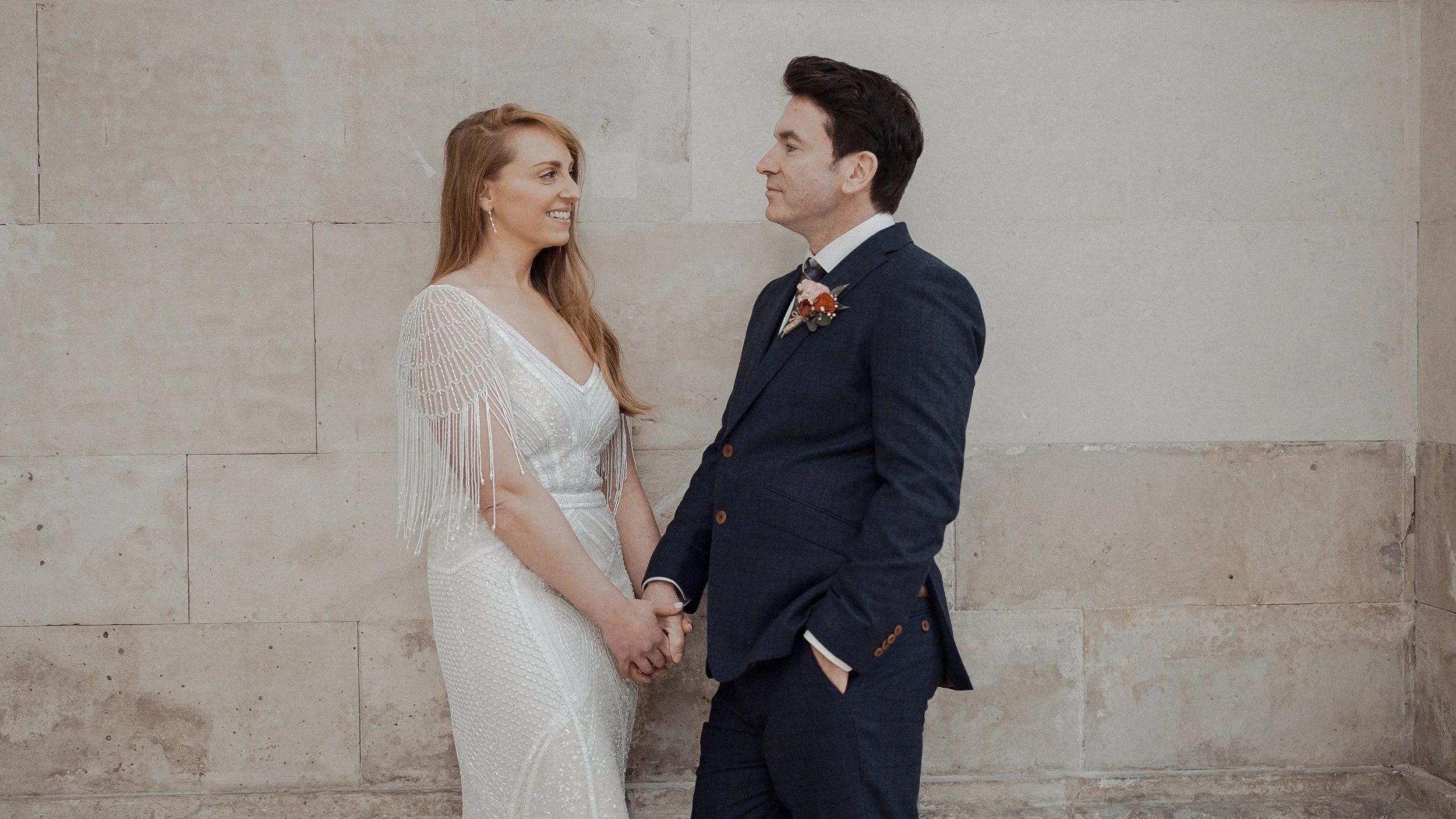 Bride and groom holding hands against the Georgian stone wall of Dublin City Hall