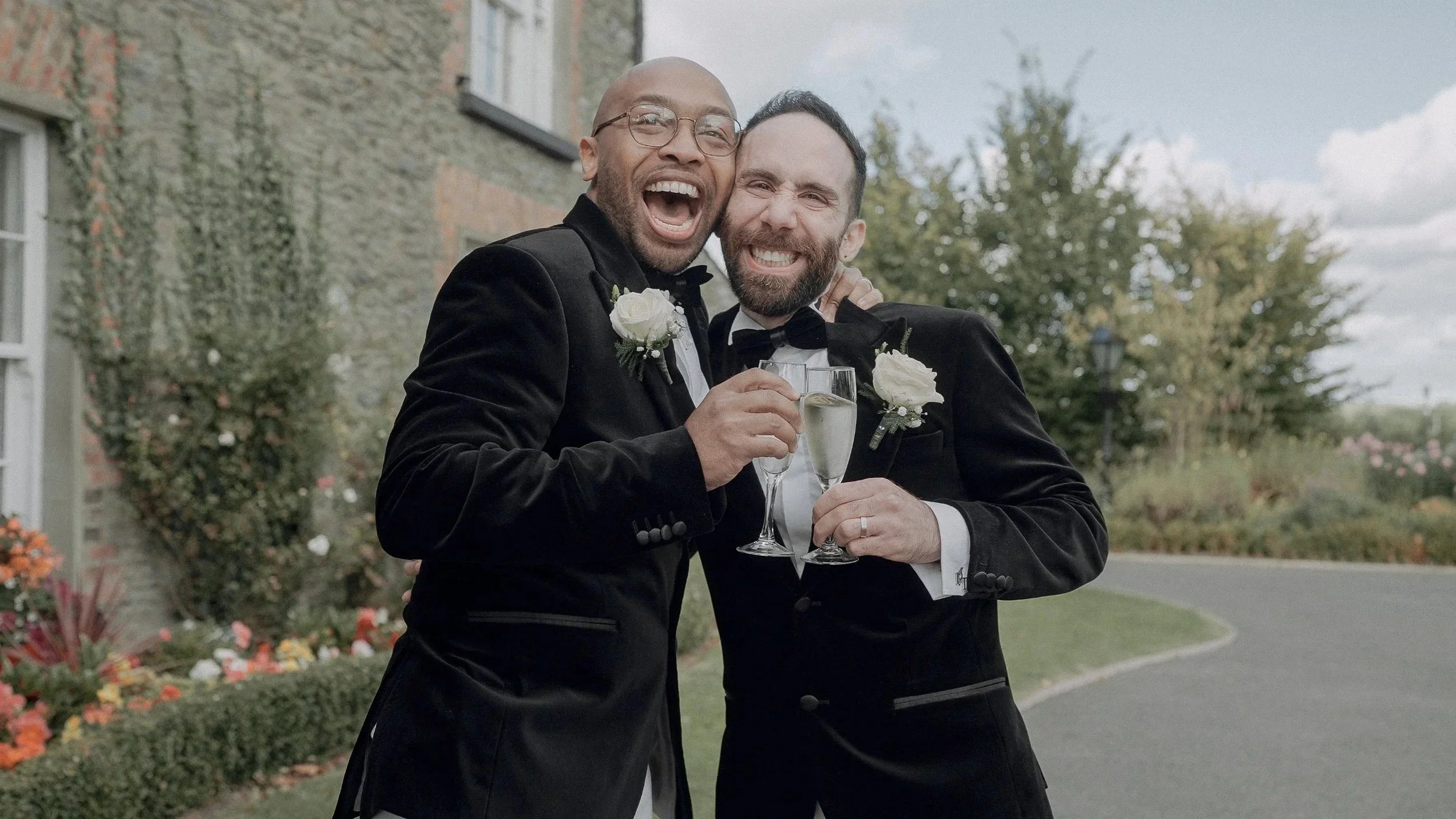 Peris and Trevor laughing with glasses of champagne outside Darver Castle after their wedding ceremony