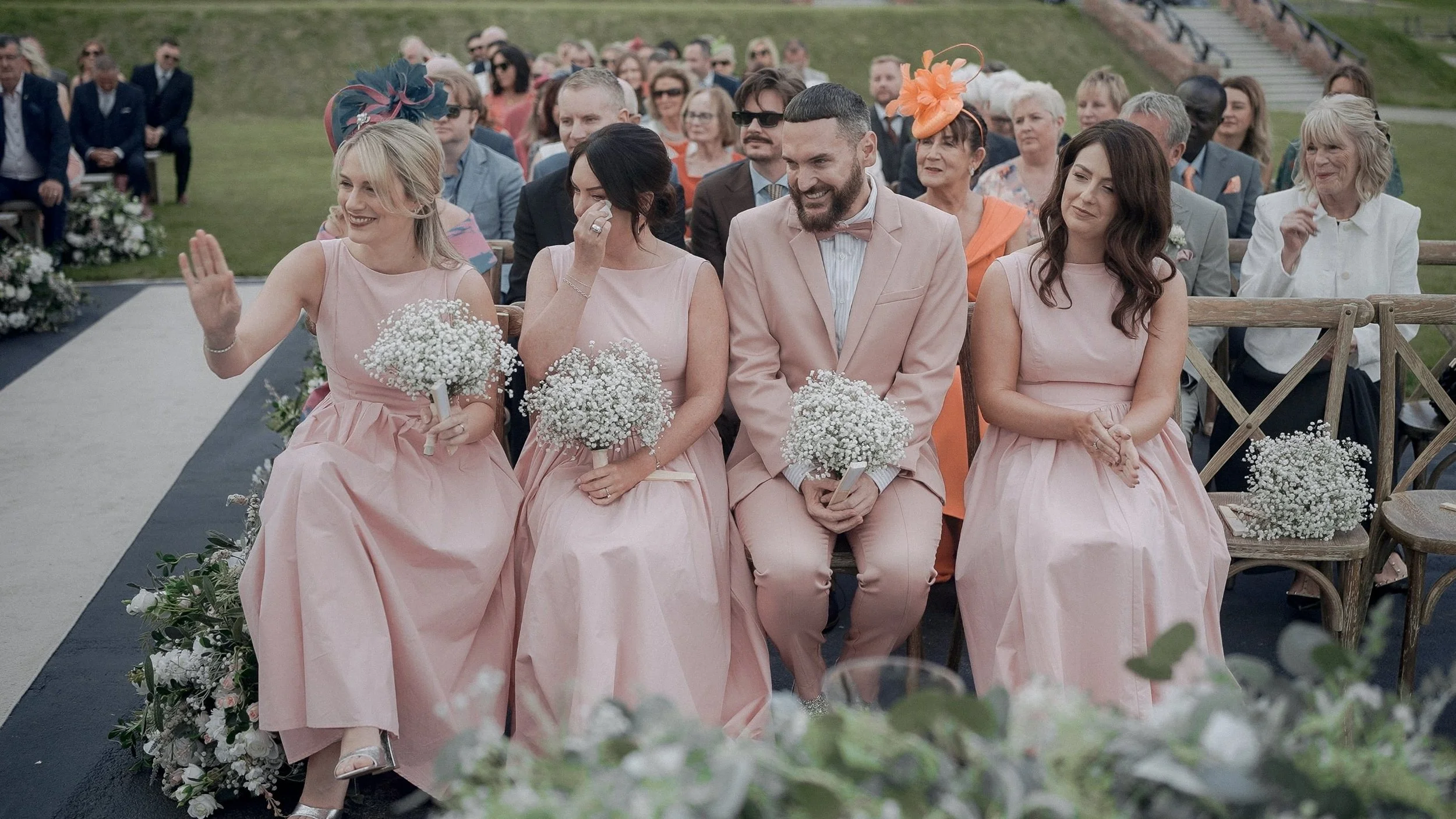 Bridal party in blush pink with gypsophila bouquets at the outdoor wedding ceremony at Glasson Lakehouse