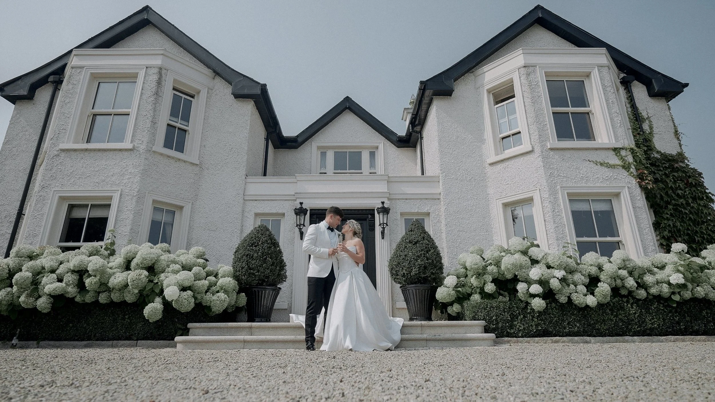 Taylor and Jack in front of their family home on The Curragh, Co. Kildare, surrounded by white hydrangeas