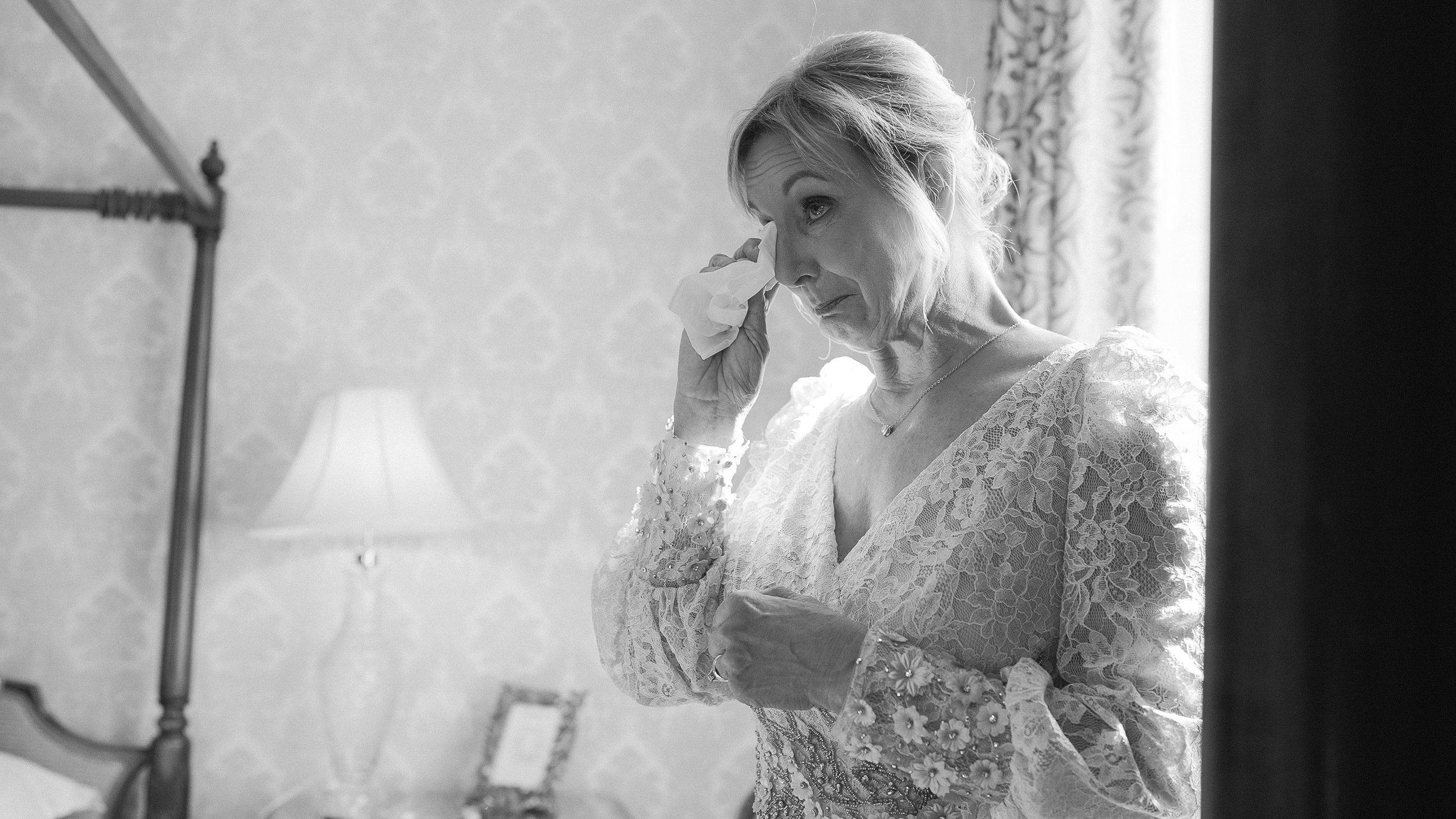 Emotional mother of the bride wiping a tear on the wedding morning at Waterford Castle, black and white