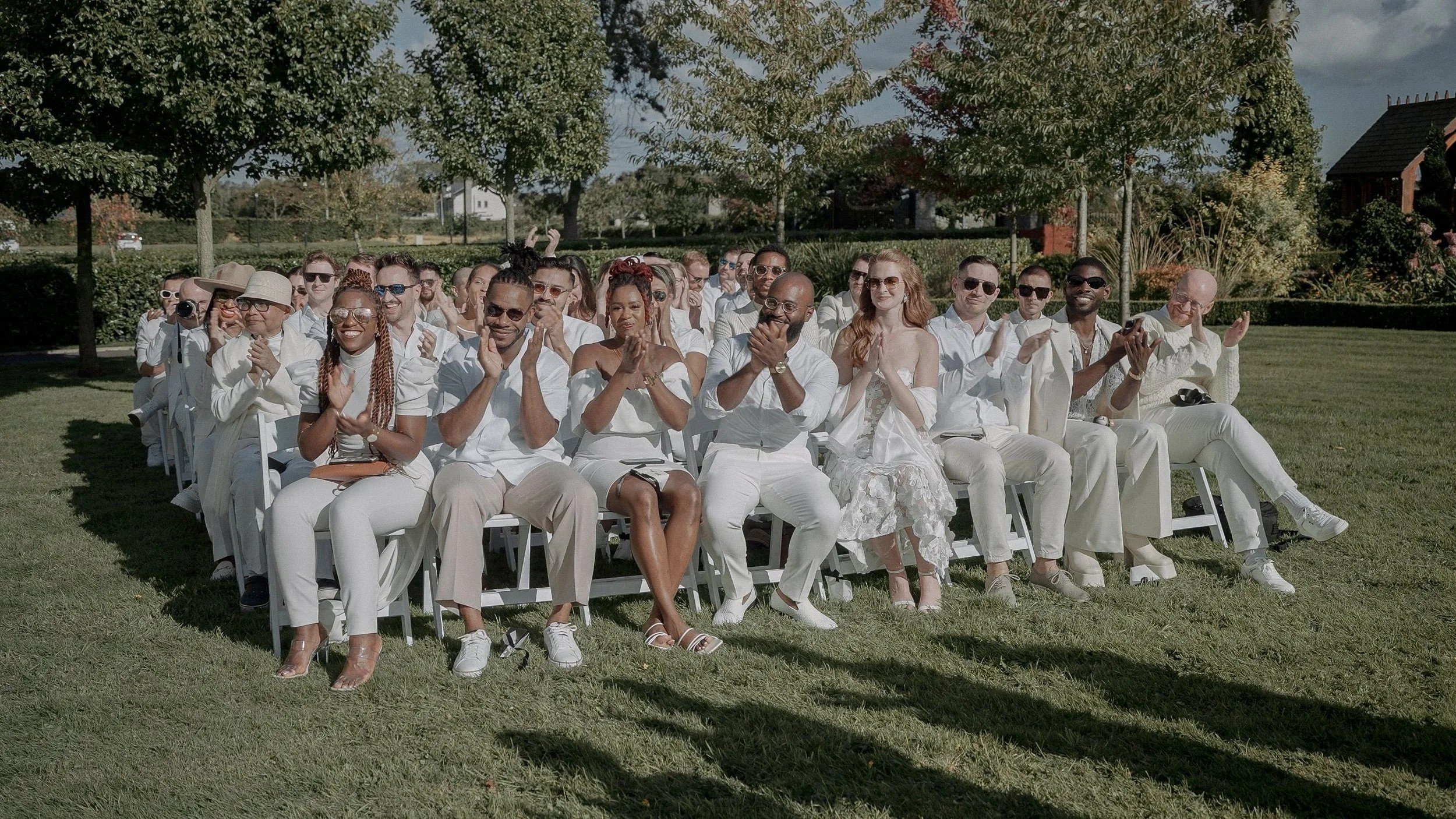 Guests dressed in white applauding at the outdoor wedding ceremony on the lawn of Darver Castle, Co. Louth