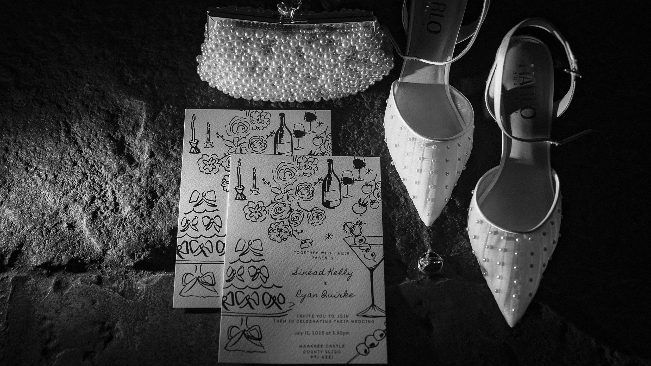 Hand-drawn wedding invitations, pearl clutch and pearl bridal shoes on stone at Markree Castle, black and white