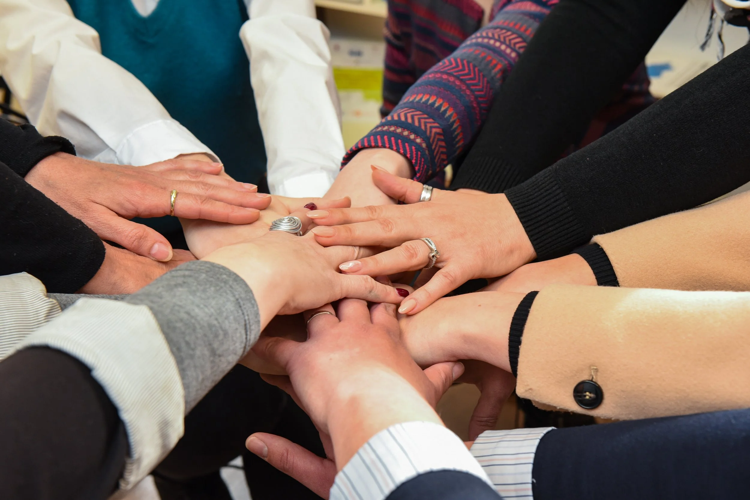 Several people with hands stacked together, symbolizing unity or teamwork.