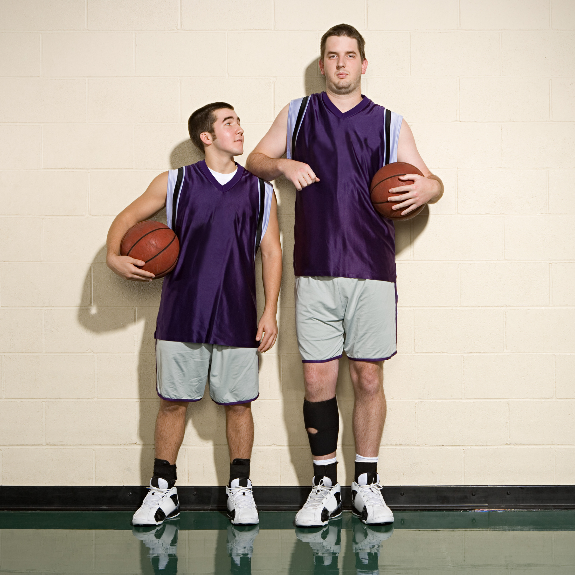 kort mann ved siden av en høyere mann poserer på basketballbanen