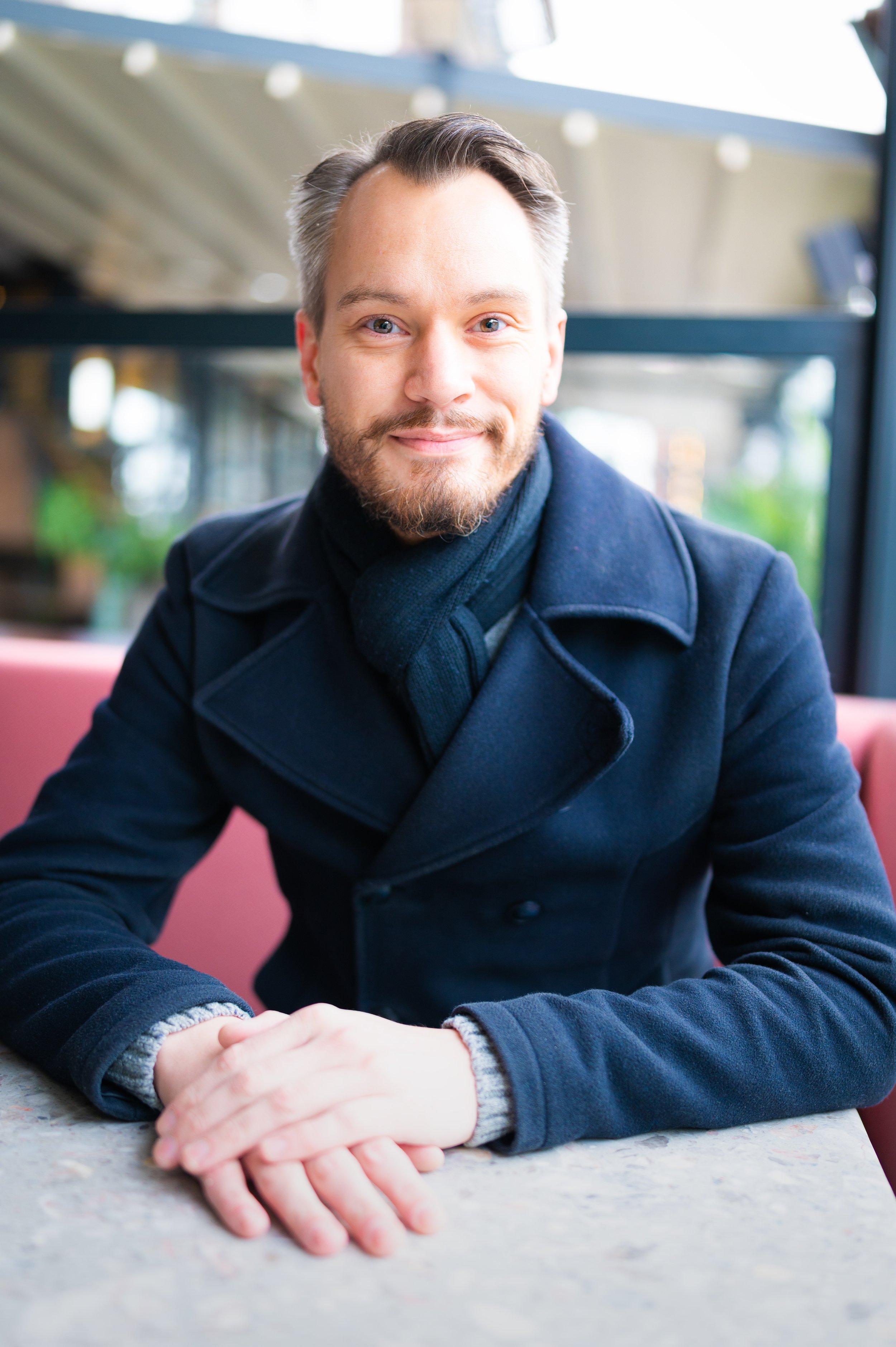 man in a nice coat leaning slightly over a table