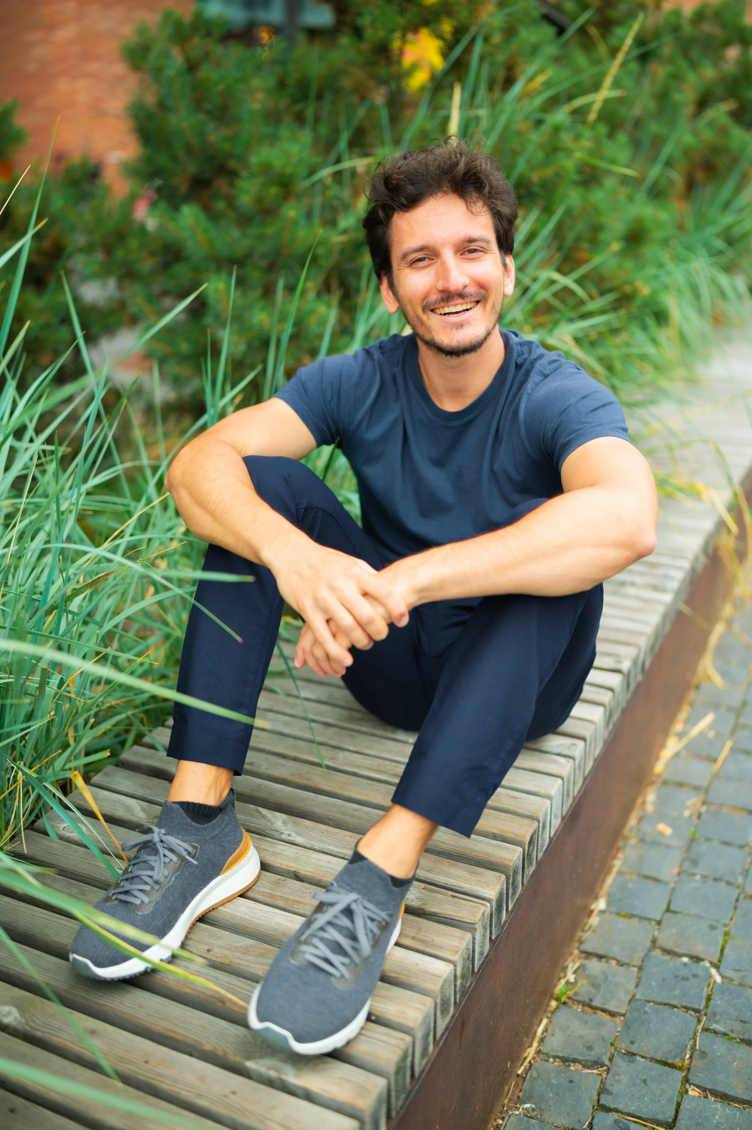 man sitting in oslo on a bench with plants behind him