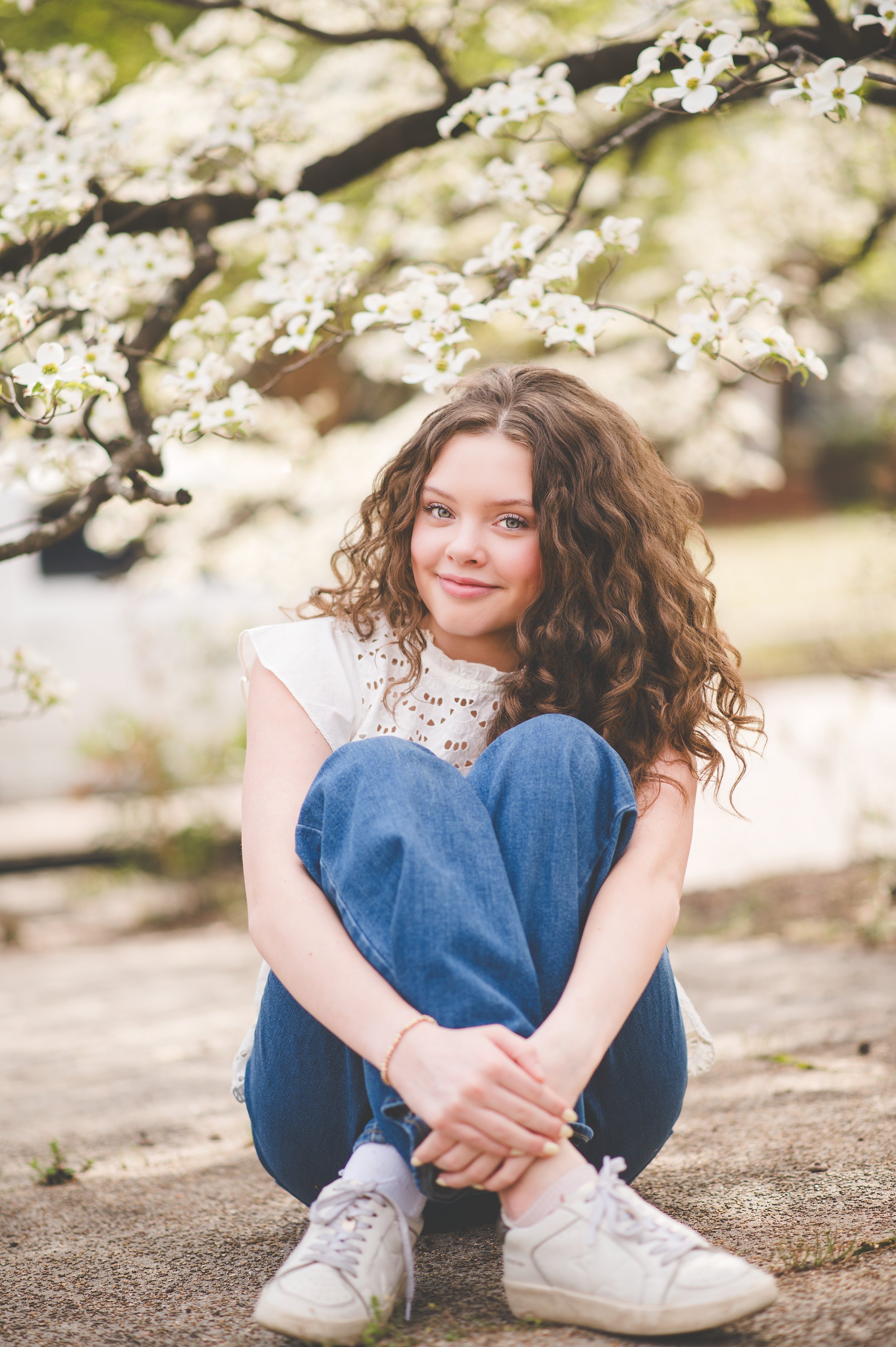 A young girl smiling and posingplayfully outdoors in a grassy field during sunset.