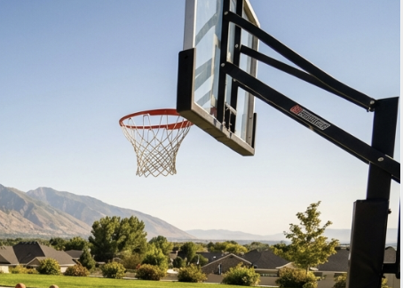 An outdoor basketball hoop with a clear blue sky and mountain scenery in the background.