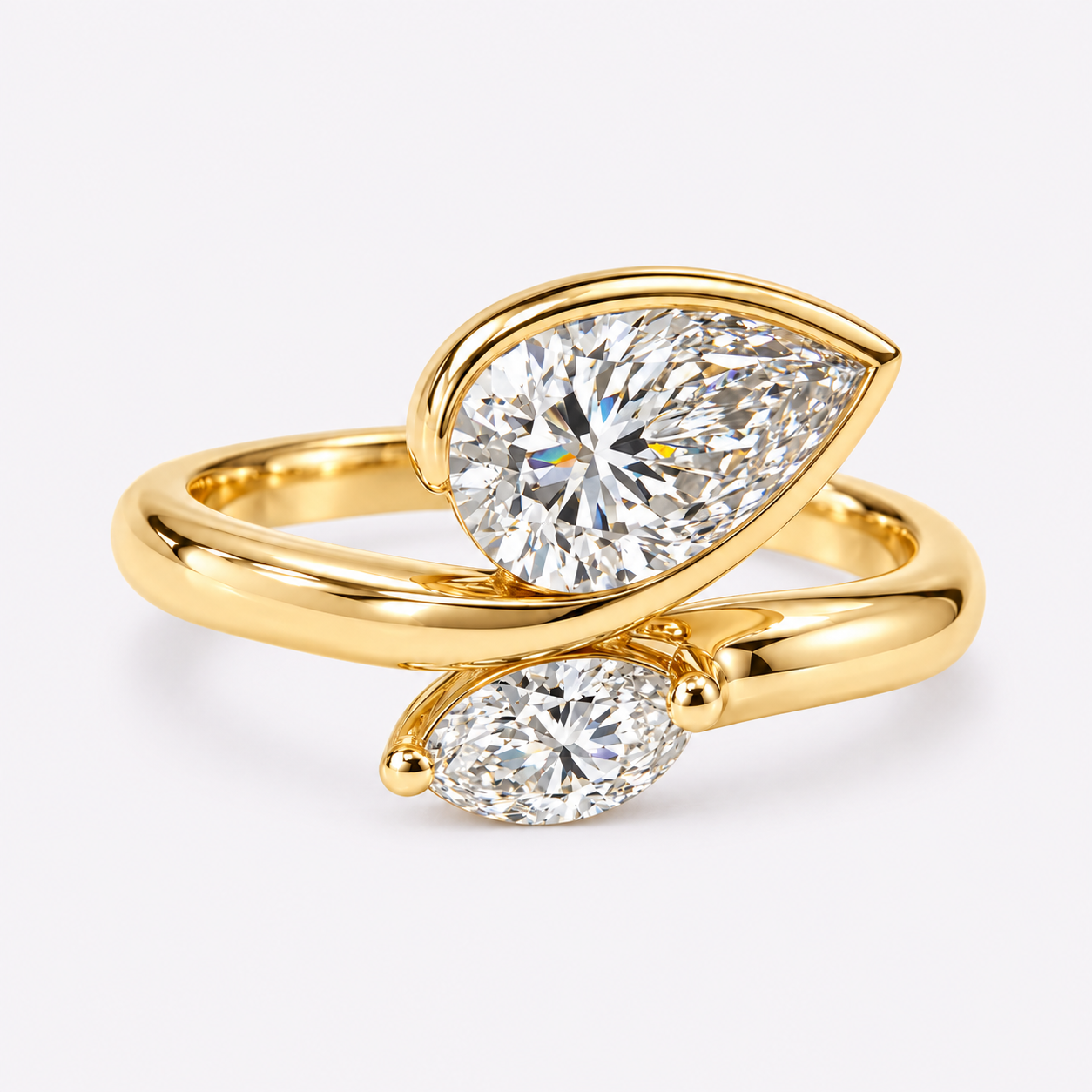 Close-up of two gold rings, each with a large teardrop-shaped diamond, against a plain white background.
