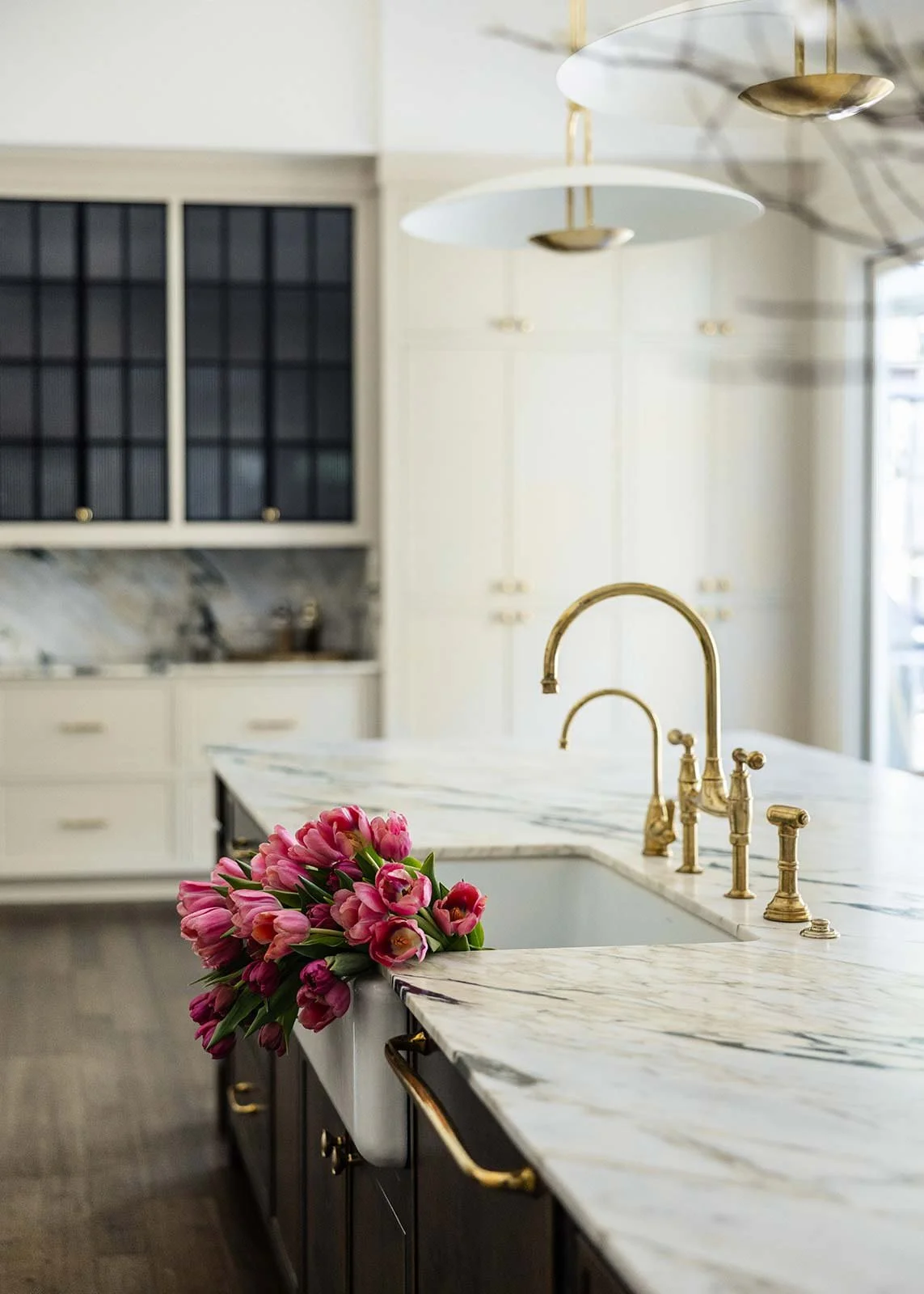 High-end kitchen renovation in Indian Springs Alabama showcasing an farmhouse sink with premium brass fixtures on a marble island.