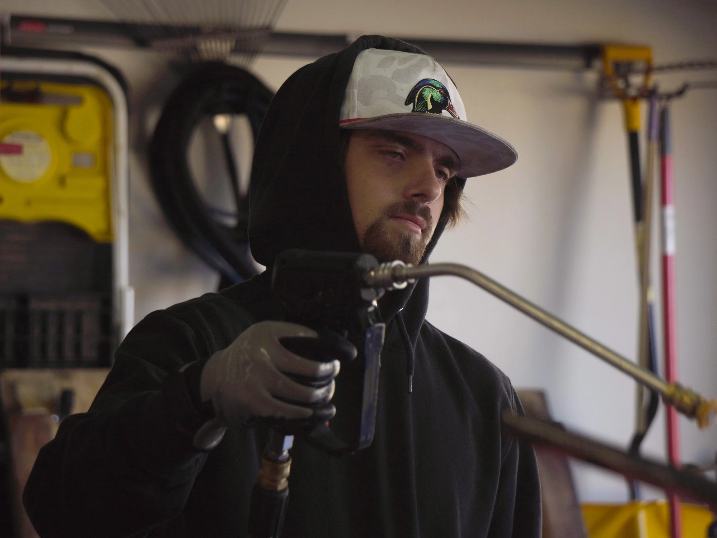 Dalton holding a pressure washing gun, spraying a vehicle during a detail