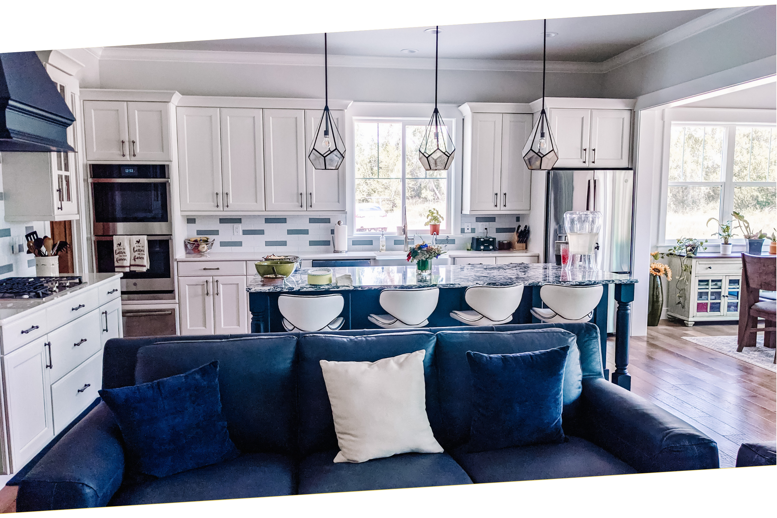 Modern farmhouse kitchen with white cabinets, large island with bar stools, pendant lighting, and stainless steel appliances. Custom home designed by LGA Studios. 