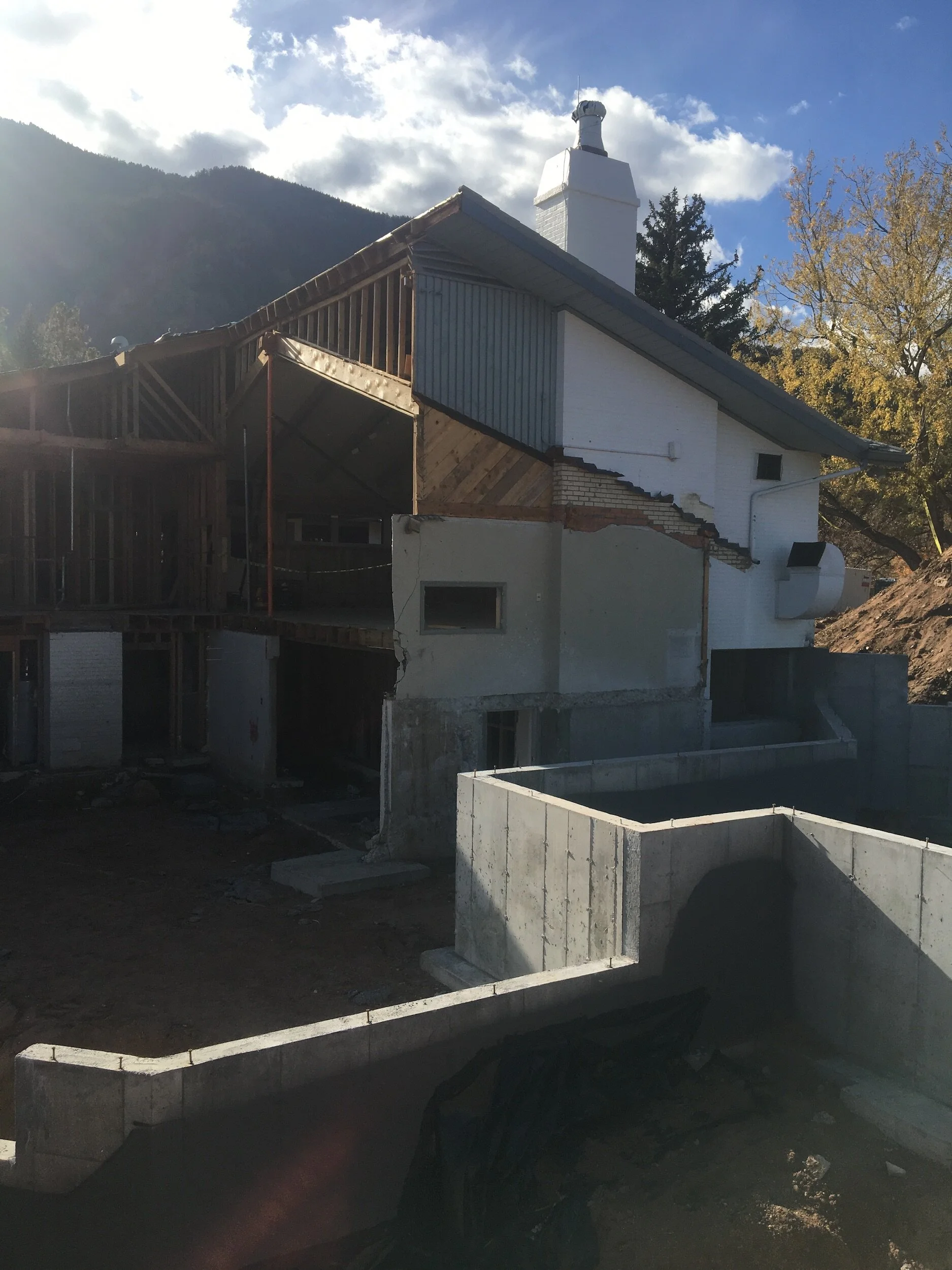 Partially constructed or renovated house with exposed wooden frame, concrete foundation, and visible chimney in Colorado designed by LGA Studios.