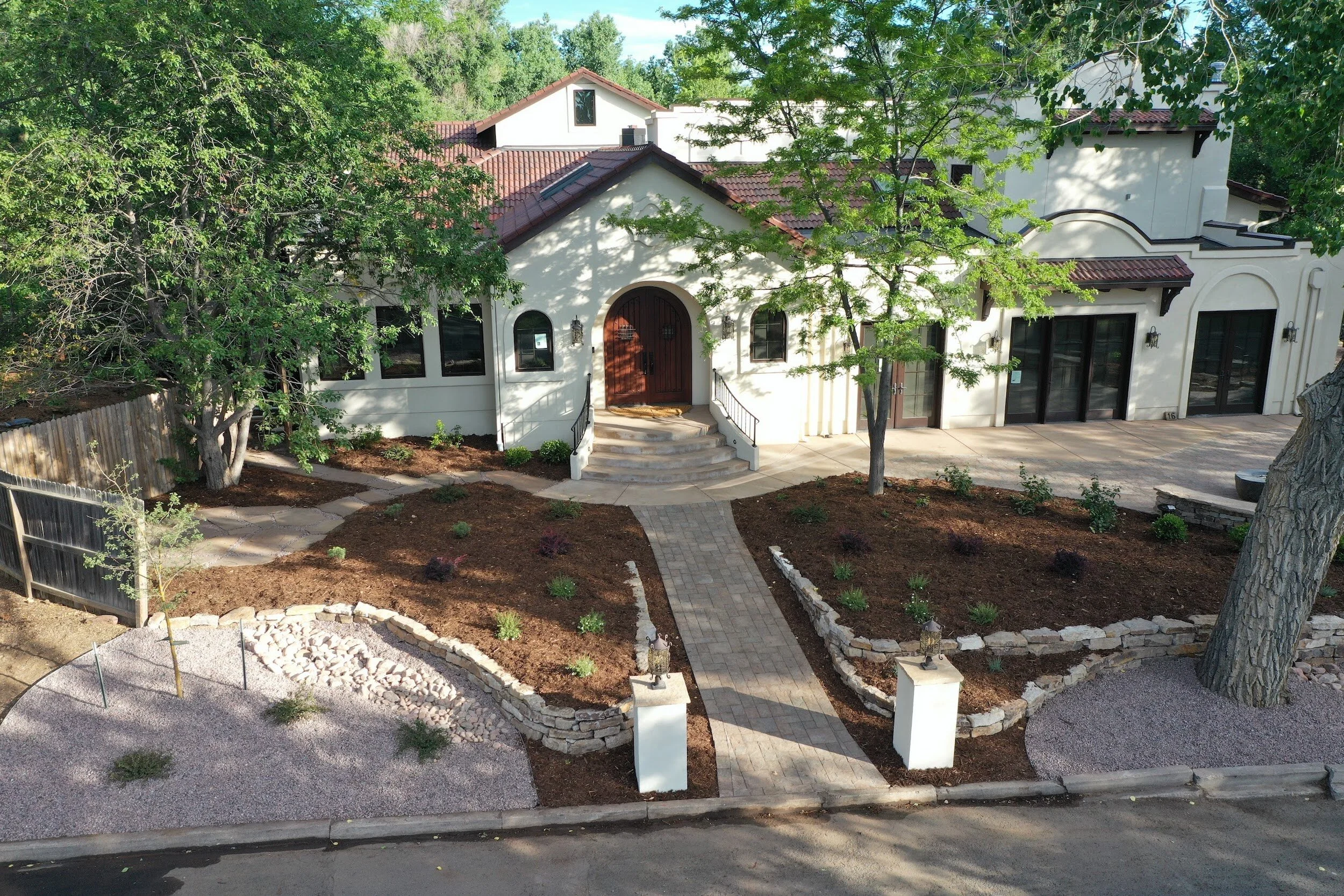 Aerial view of a Mediterranean-style house with a red-tiled roof, arched windows, and a wooden front door. Custom home remodel designed by LGA Studios in Broadmoor, Colorado Springs.