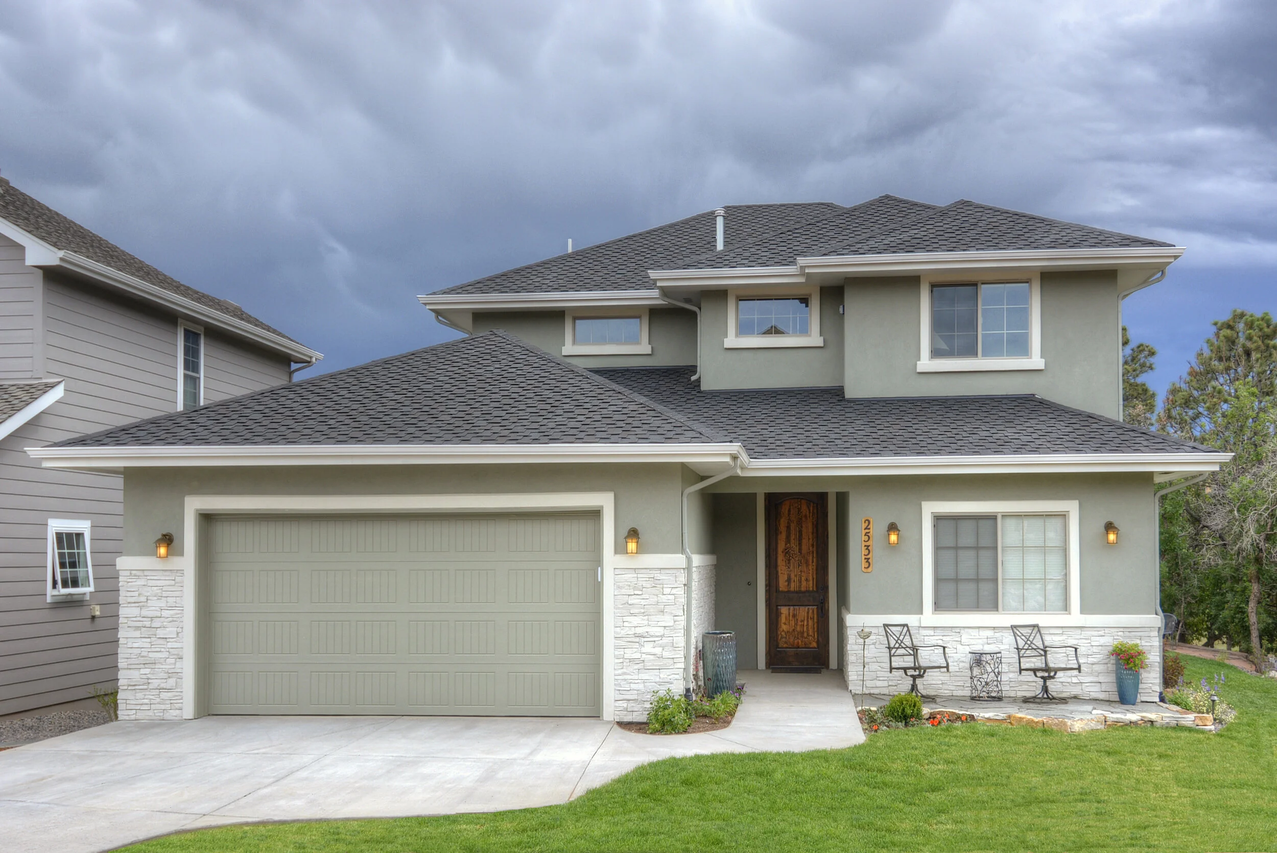 Modern two-story house with gray siding, a dark shingled roof, and an attached garage. Custom home in Colorado Springs designed by LGA Studios. 