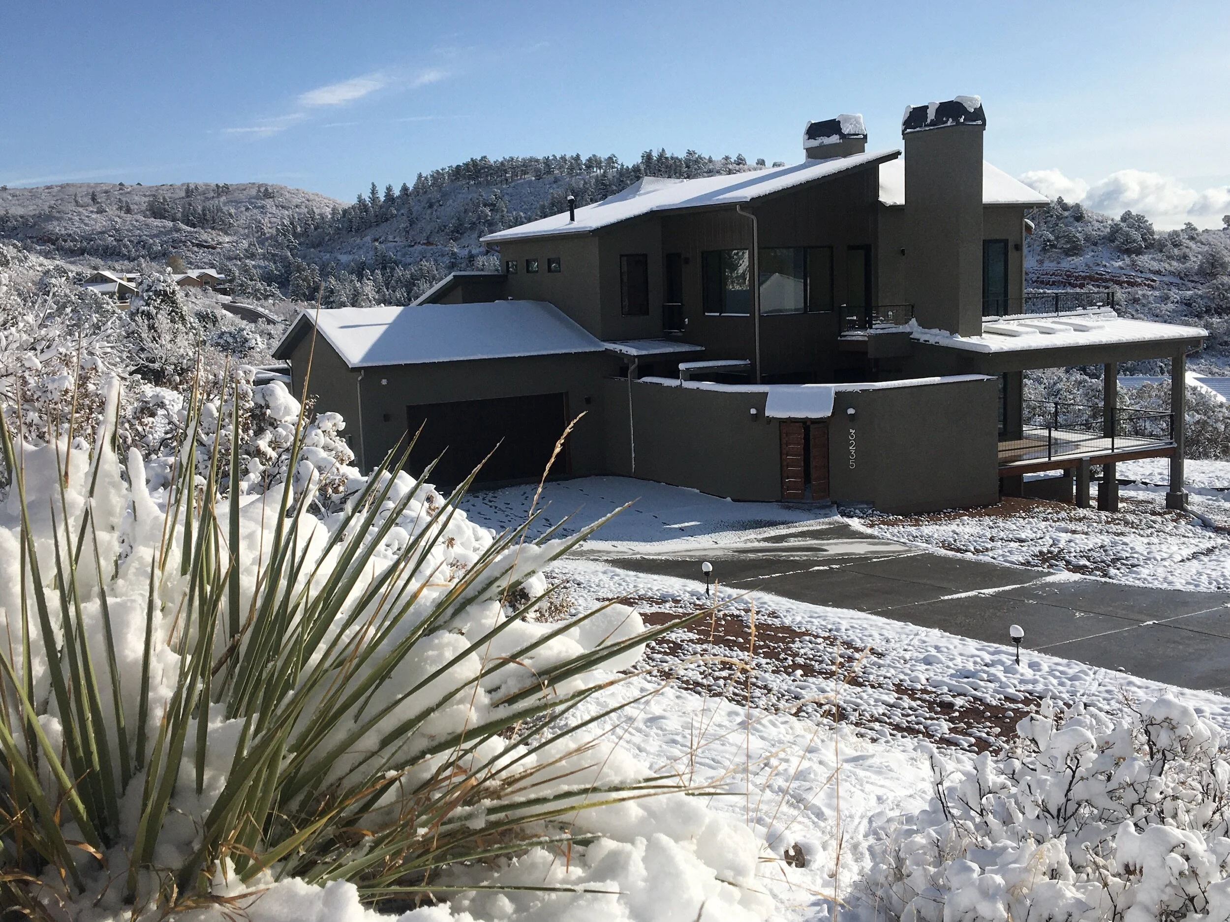 Custom hillside home designed by LGA Studios in Cedar Heights, Colorado Springs. Modern house on a snowy mountain landscape with plants and hills.