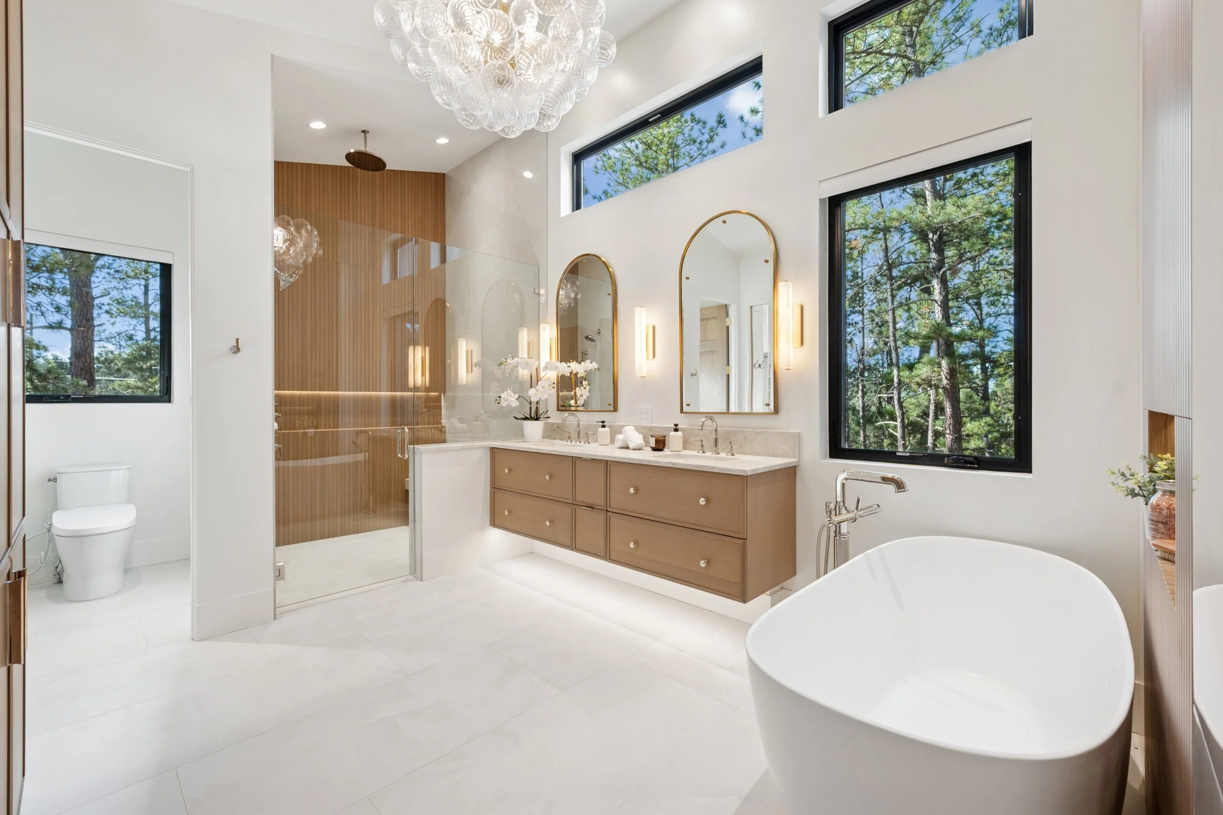 Spa bath in primary suite with warm wood and marble.