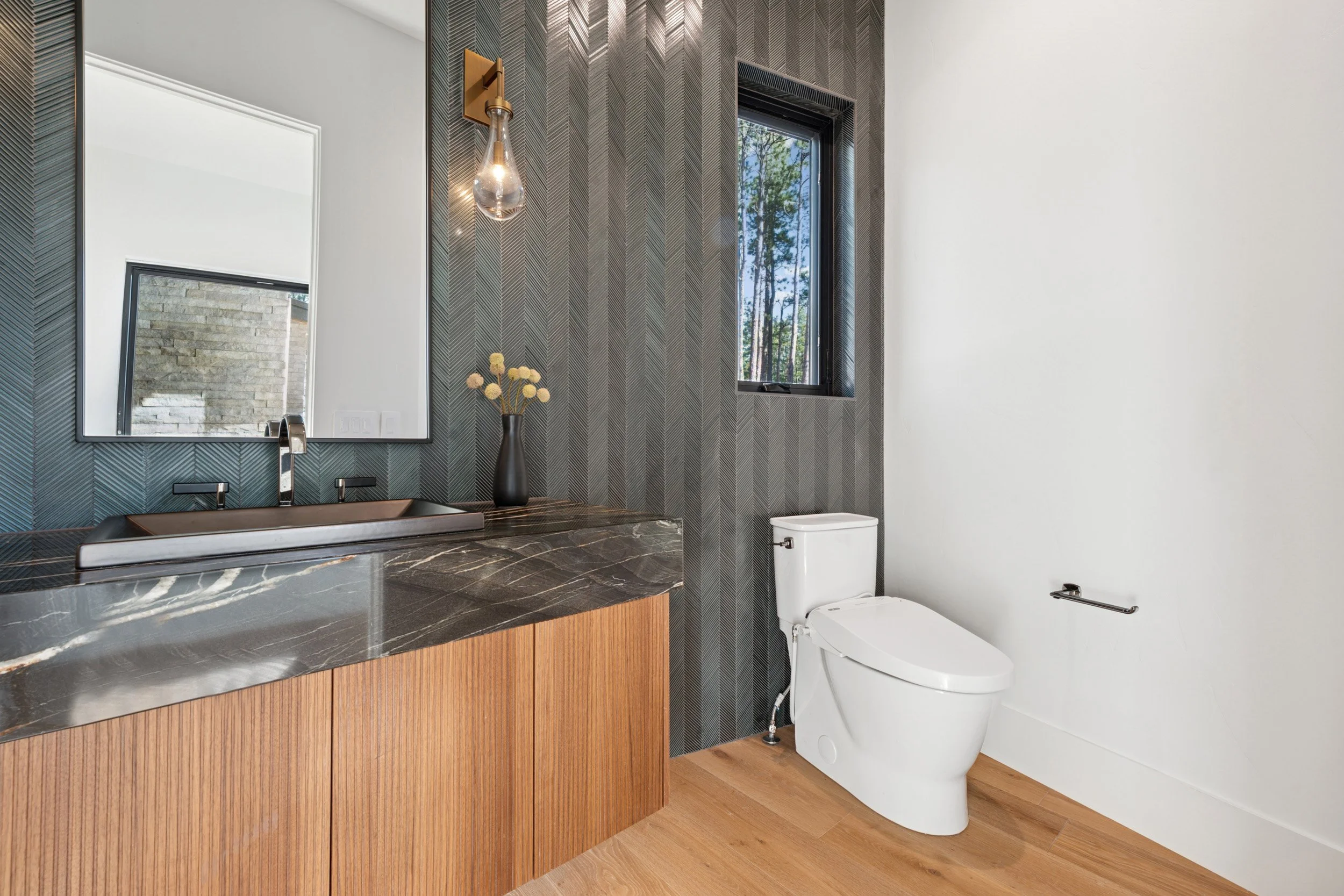 Contemporary bathroom with black textures and warm wood details.