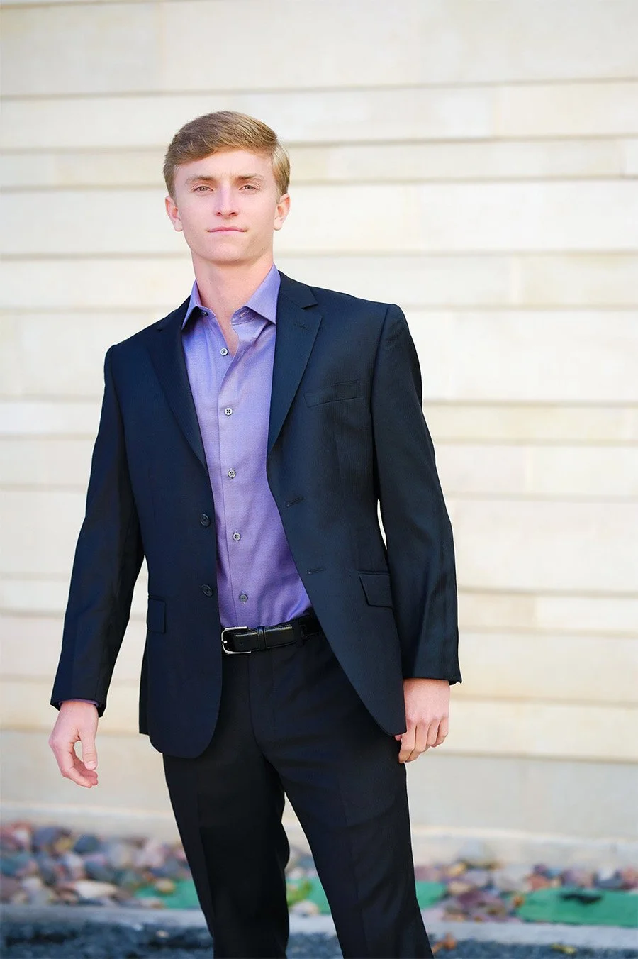 Senior teenage boy posing in formal suit with purple shirt High School graduation portrait 