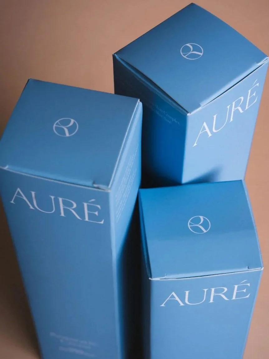 Three blue boxes with the word "AURÉ" printed on them, shown from an angle.