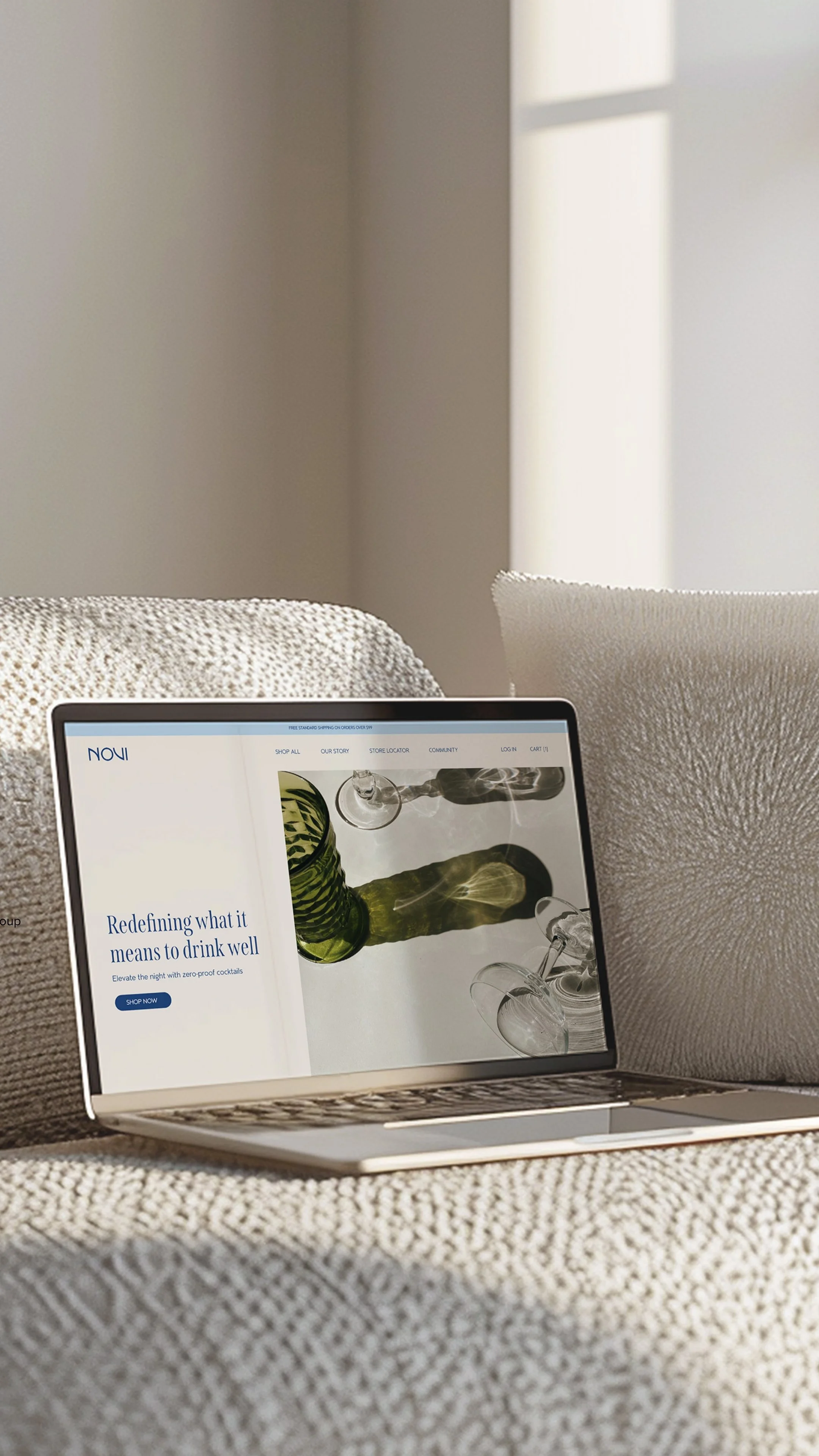 A tablet displaying a website about drinkware, resting on a beige textured couch, with sunlight casting shadows on the wall in the background.