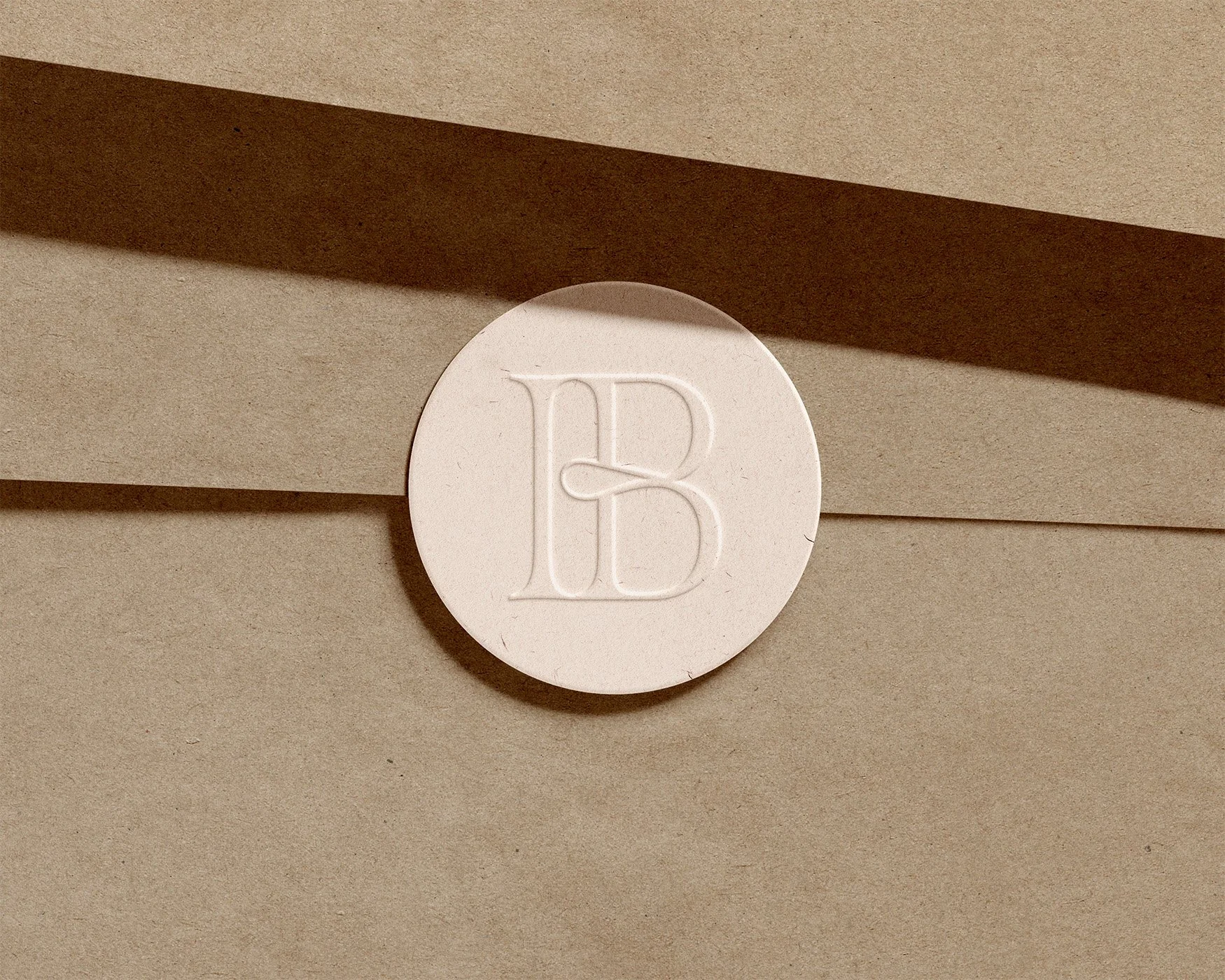 A white round pill with the letter 'B' embossed on it, resting on beige paper envelopes. A shadow cast by a strip of brown paper is visible above the pill.