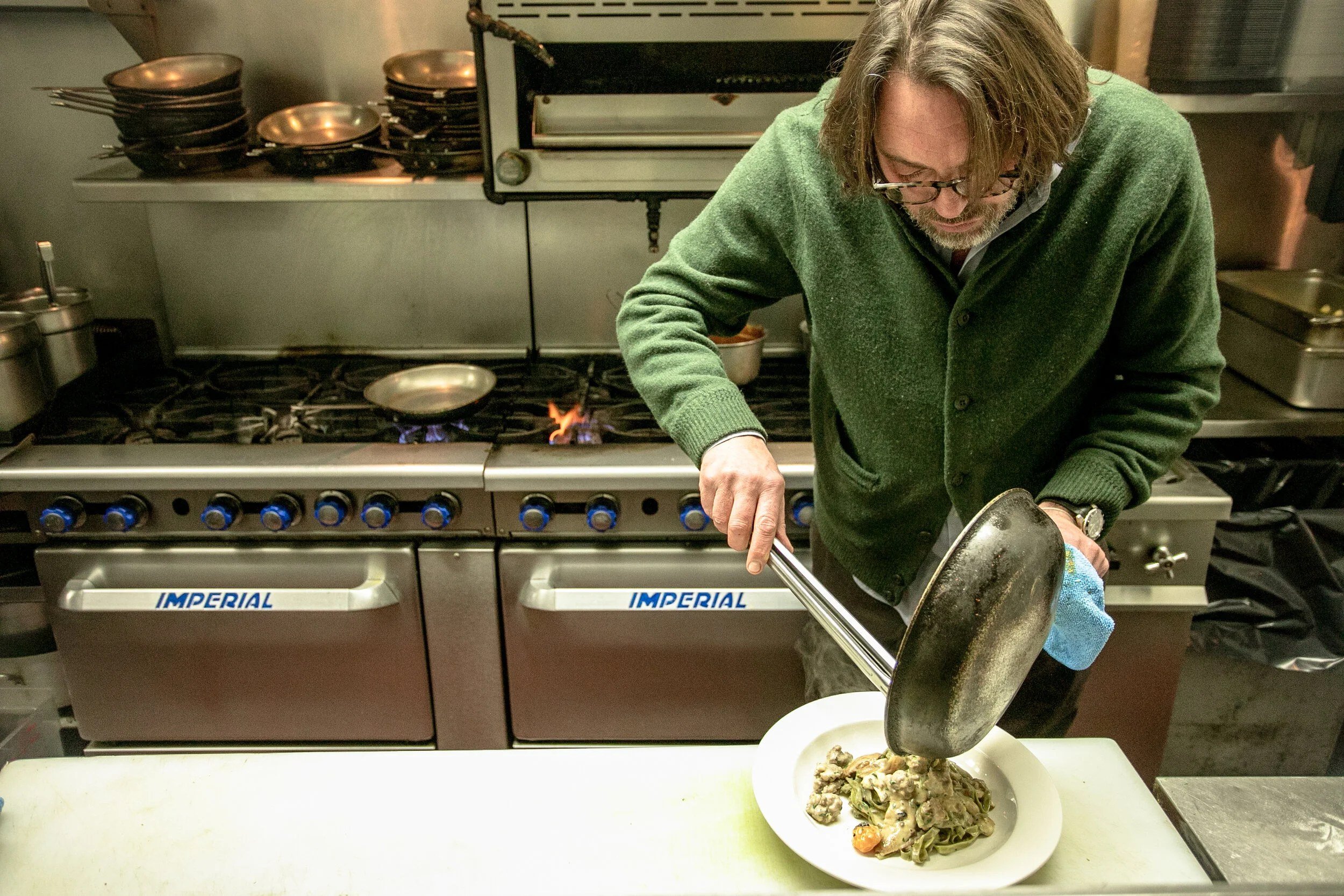 Chef plating handmade pasta in the kitchen at Scottadito Osteria Toscana, Park Slope, Brooklyn