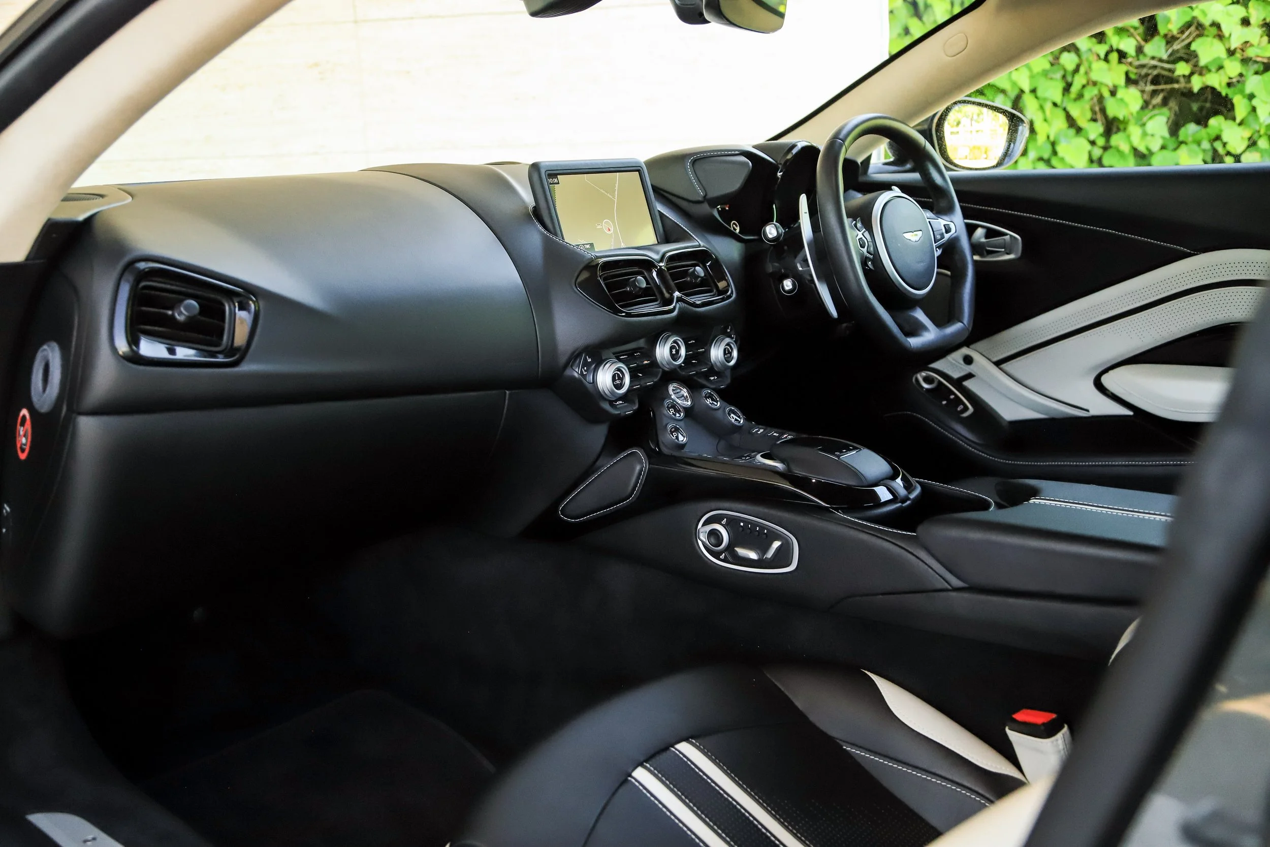Interior of a luxury car with black and white leather seats, a digital dashboard, a navigation screen, and various control buttons.