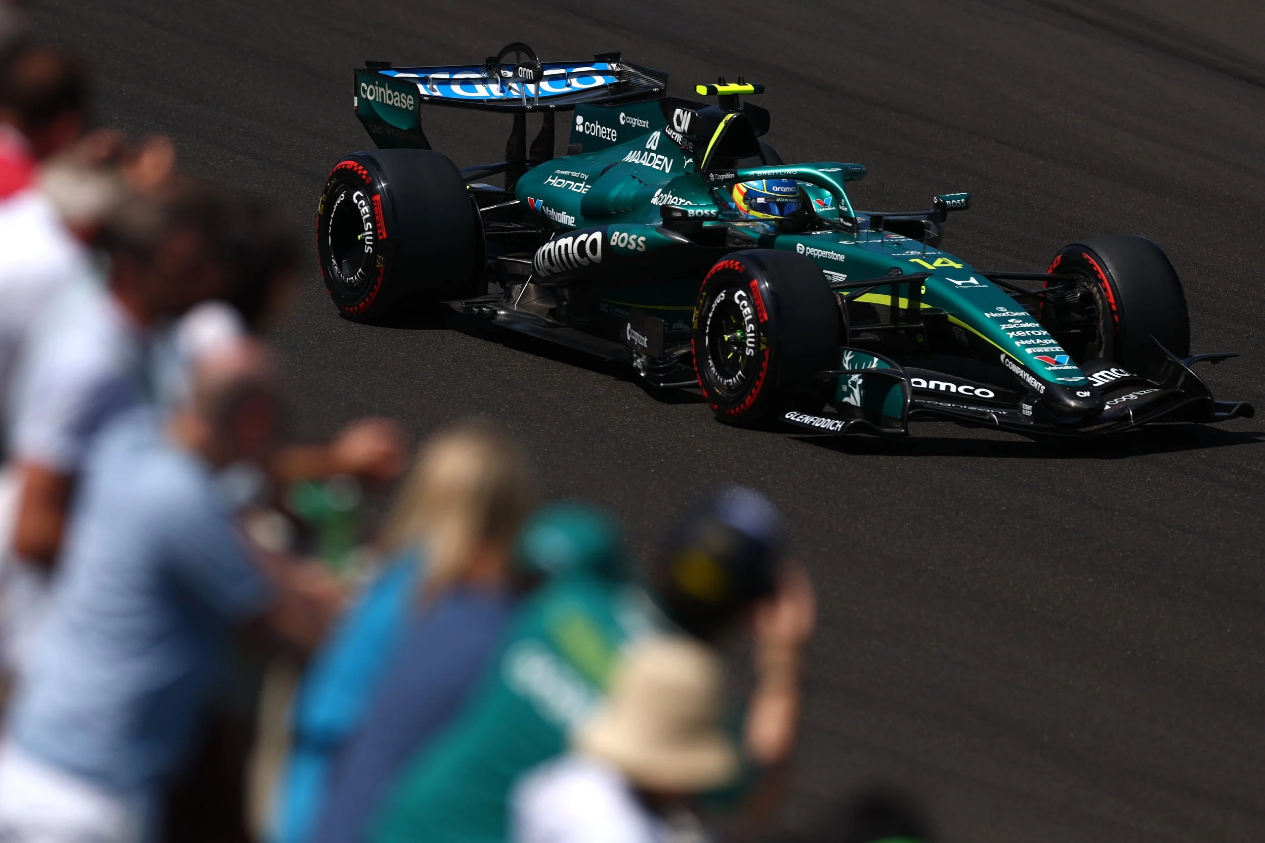 A racing car on a race track with blurred spectators in the foreground.