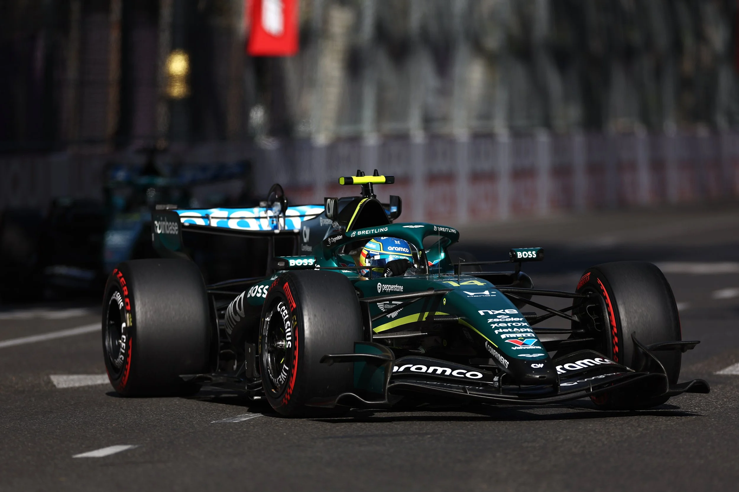 A Formula 1 race car on a city street race track with blurred spectators and advertisements in the background.