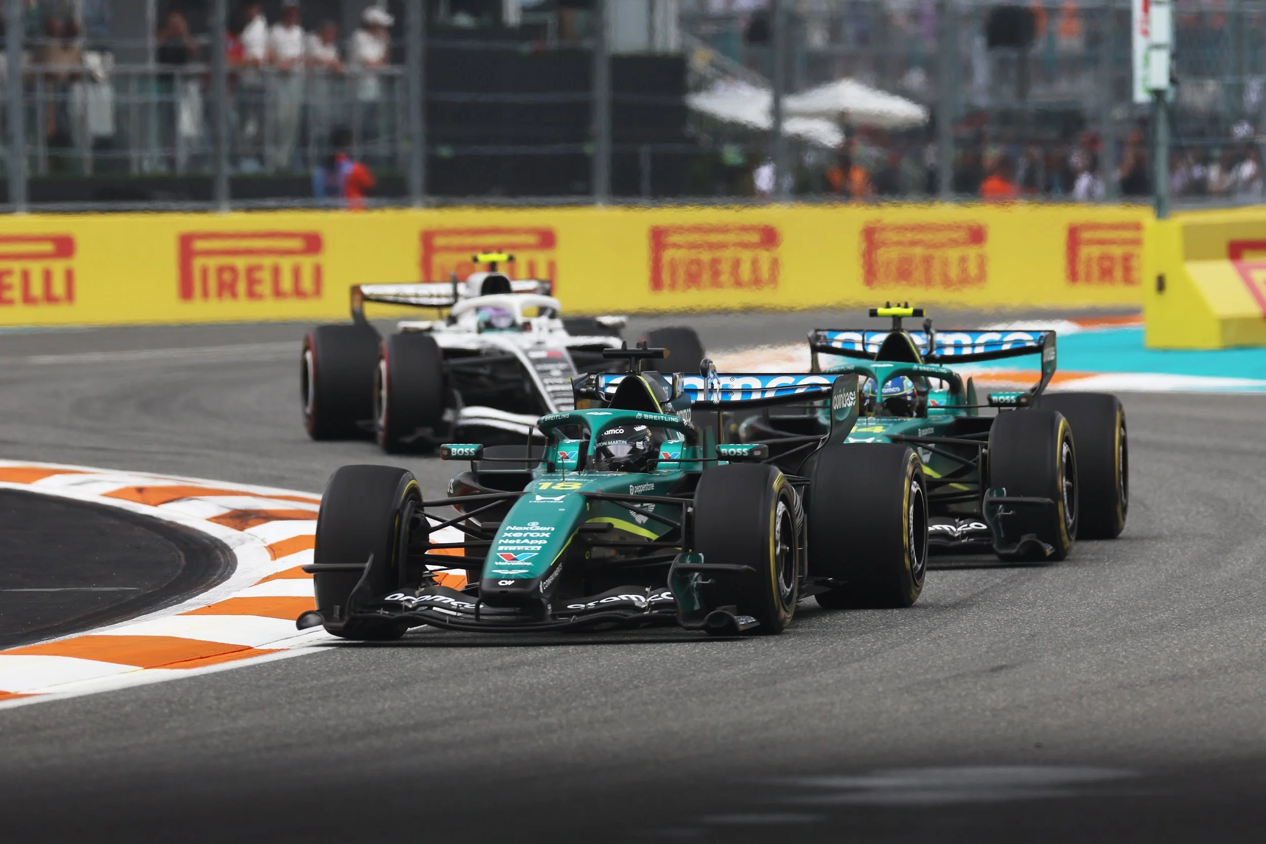 Formula 1 race cars speeding on a race track, with Pirelli advertising banners along the sides, during a race event.