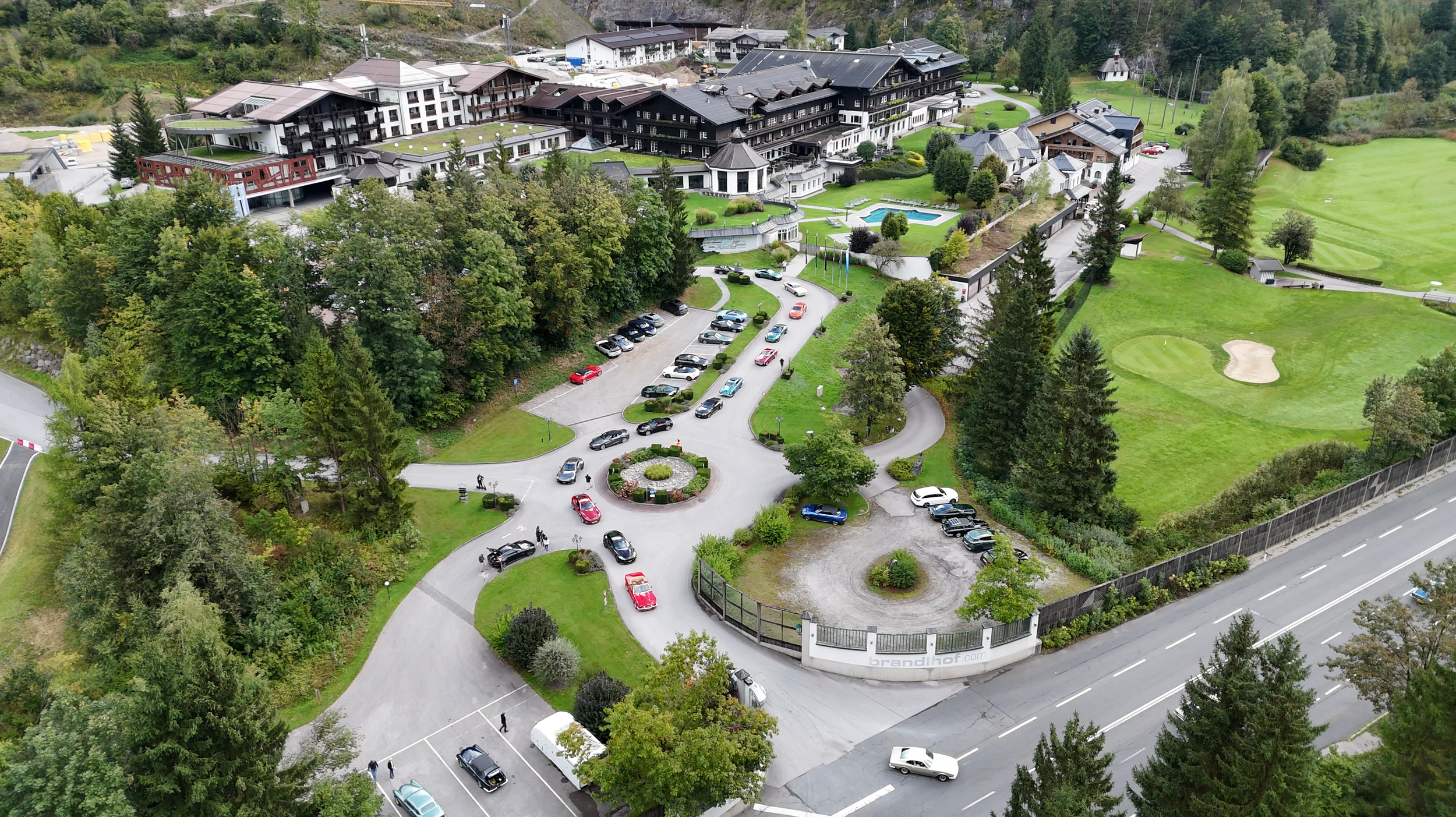 Aerial view of a large residential complex with multiple buildings, parking lots, and a golf course surrounded by trees.