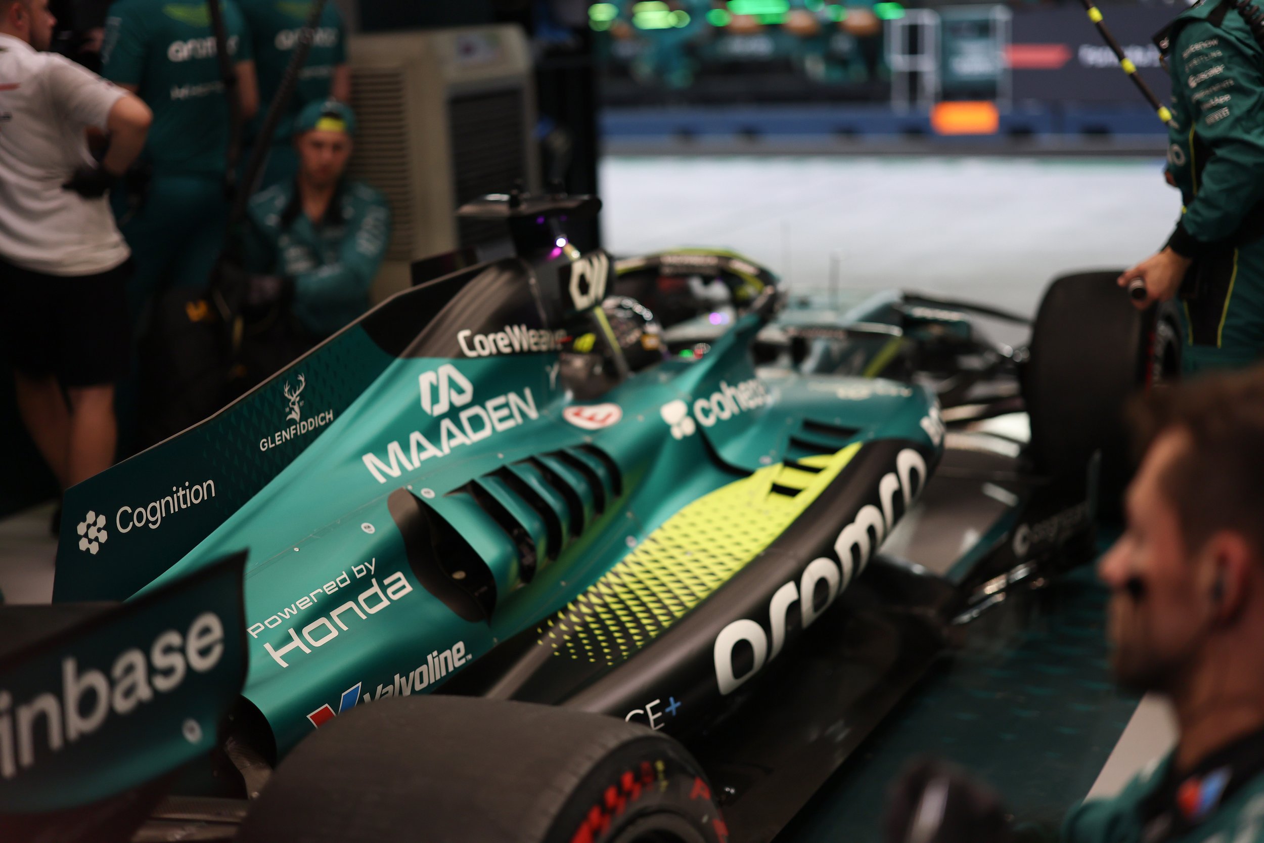 Formula 1 race car in the garage with team members around preparing the car.